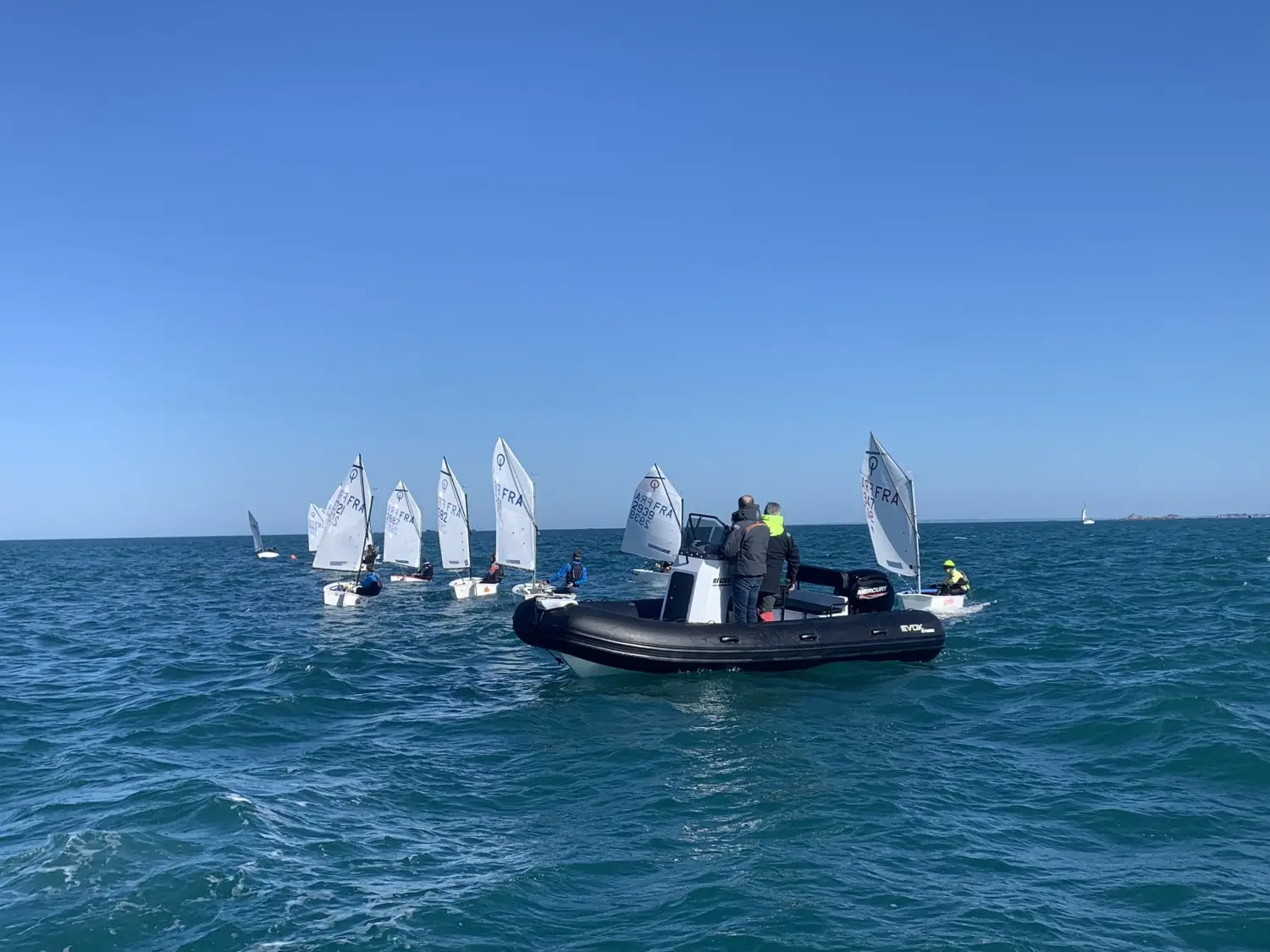 Evok Marine Evok 18 — Un bateau pneumatique à console navigue au large parmi des dériveurs.
