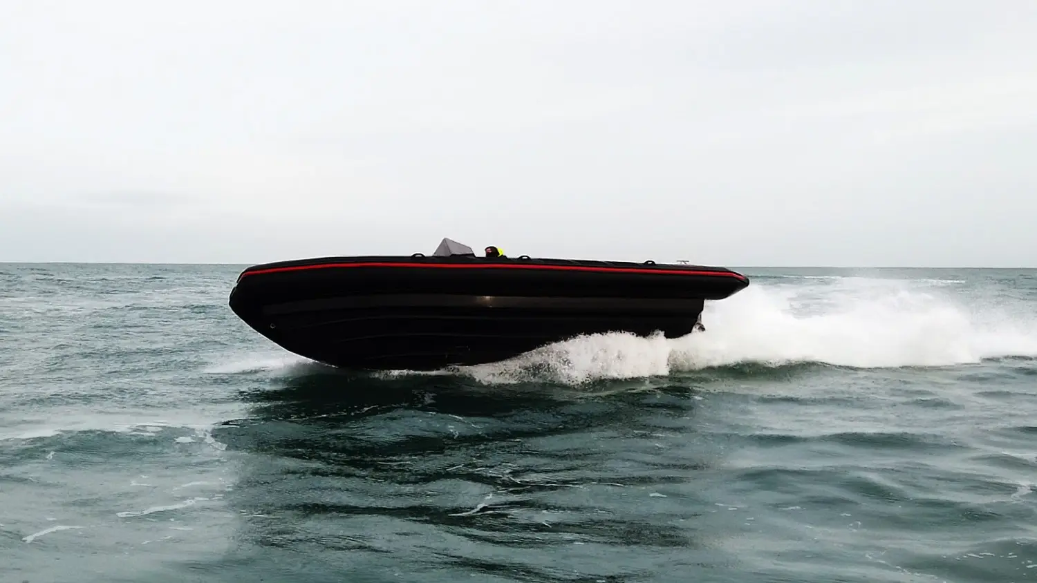 Evok Marine Evok 28 Fishing — Bateau semi-rigide noir naviguant rapidement sur une mer agitée.