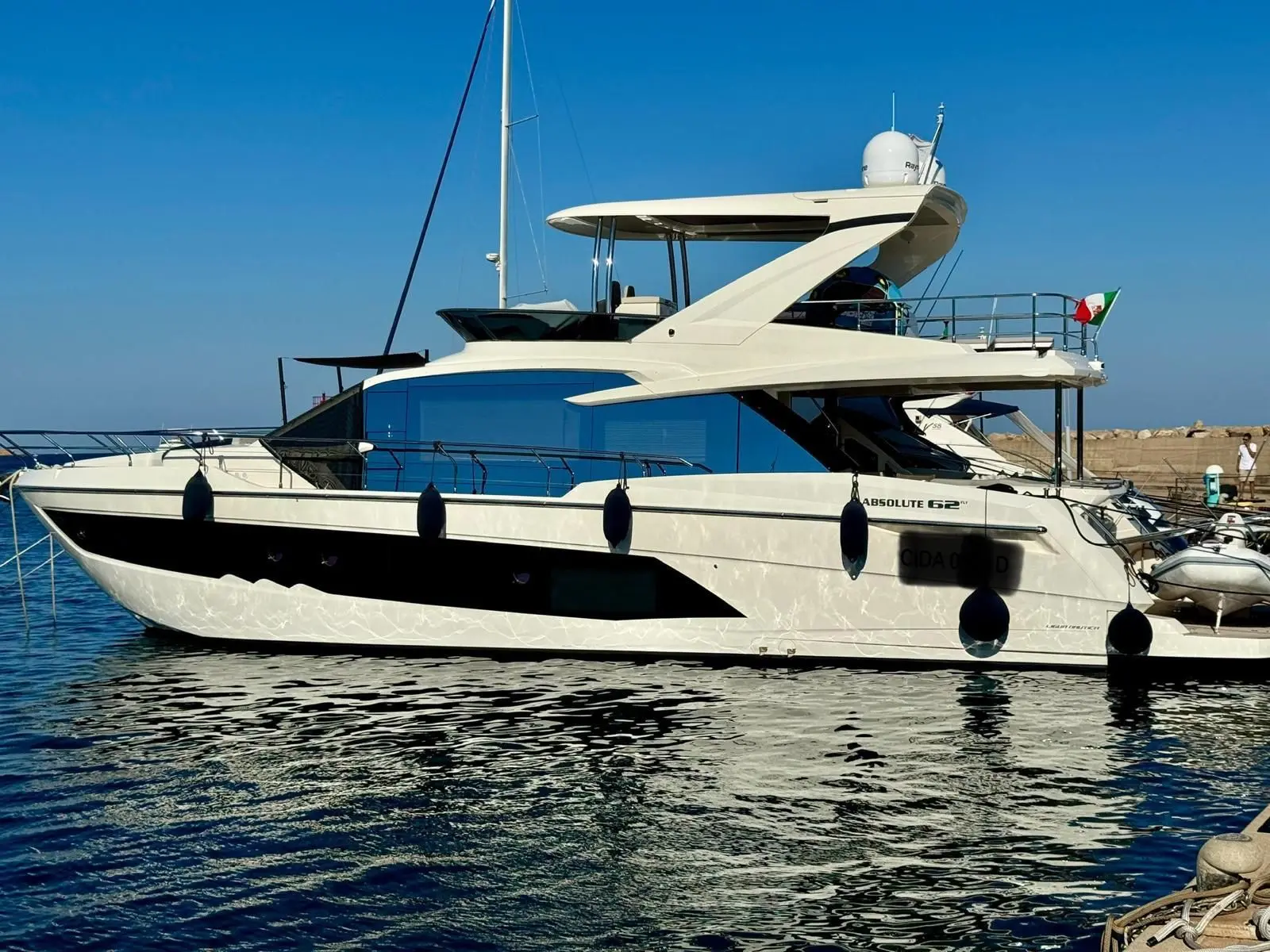 Absolute 62 Fly — Vue latérale d’un yacht à moteur blanc amarré dans un port.