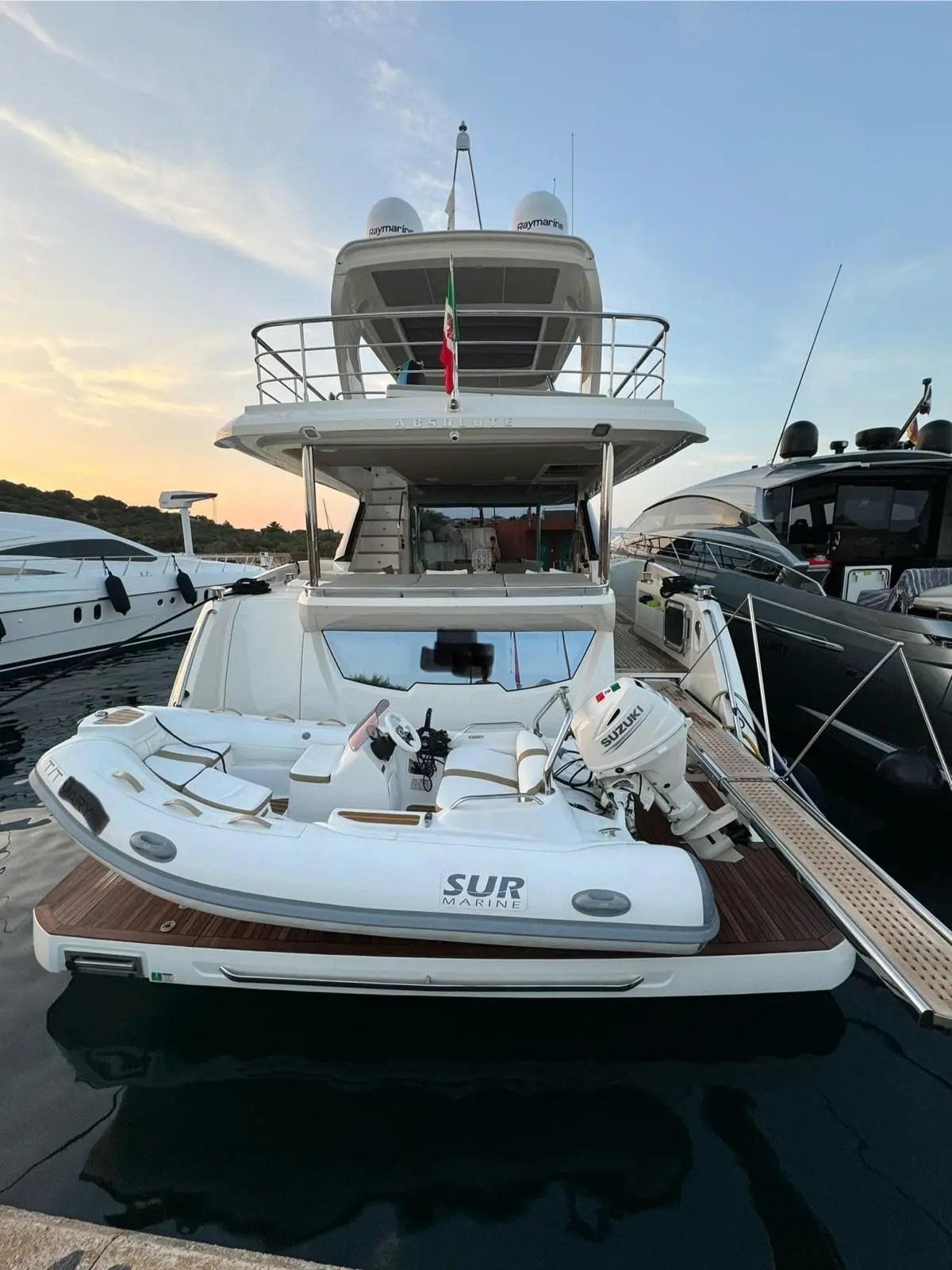Absolute 62 Fly — Vue arrière d’un bateau à moteur amarré, avec une annexe sur la plateforme.