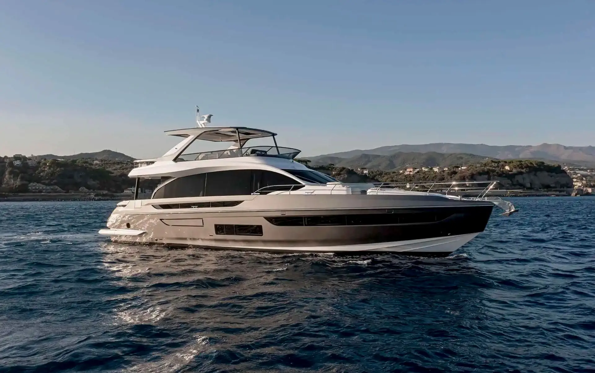 Azimut 72 flybridge — Bateau à moteur blanc vu de profil sur la mer, devant une côte montagneuse.