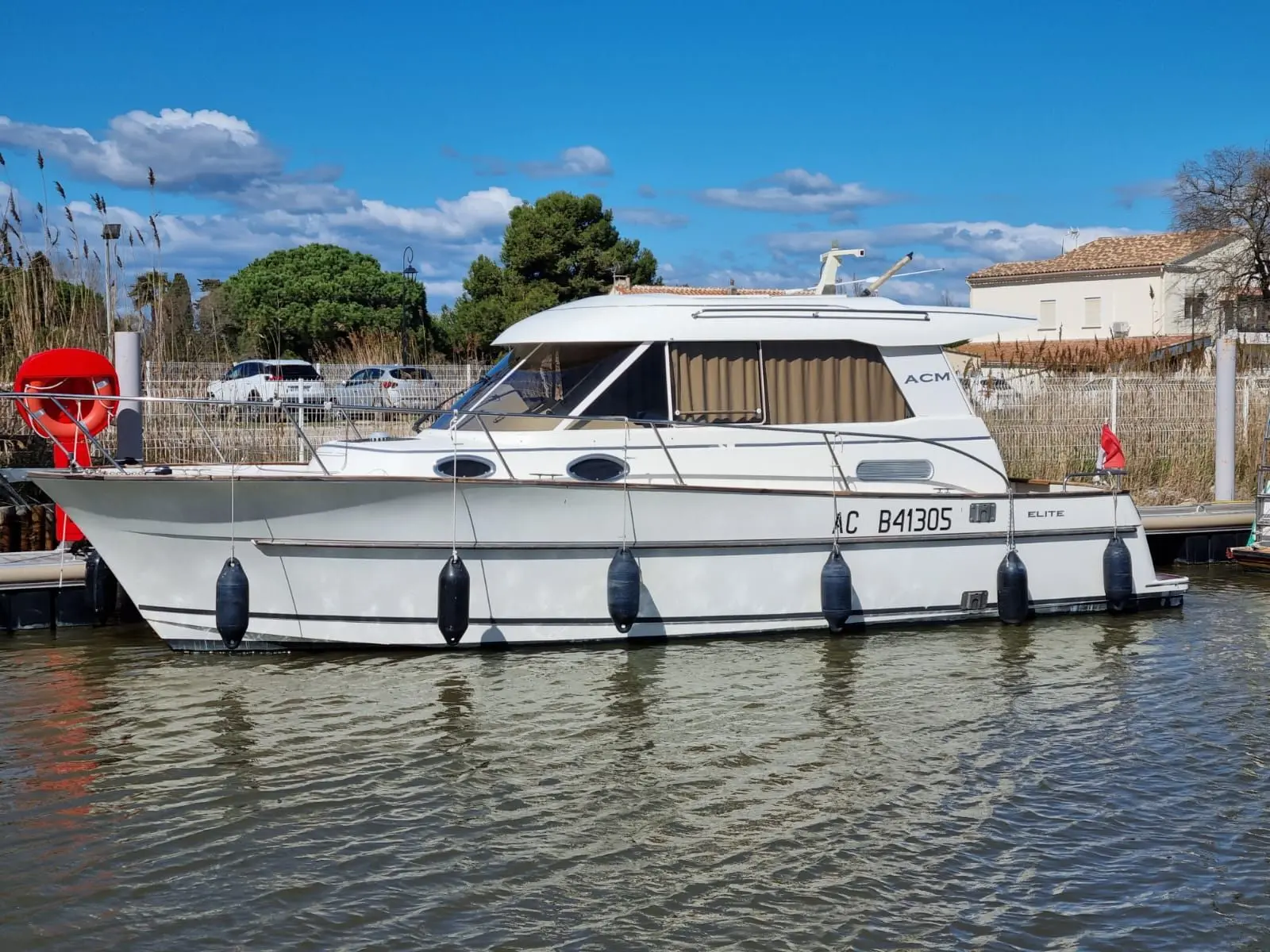 ACM Elite 31 — Bateau à moteur ACM amarré, photographié de profil dans un port.