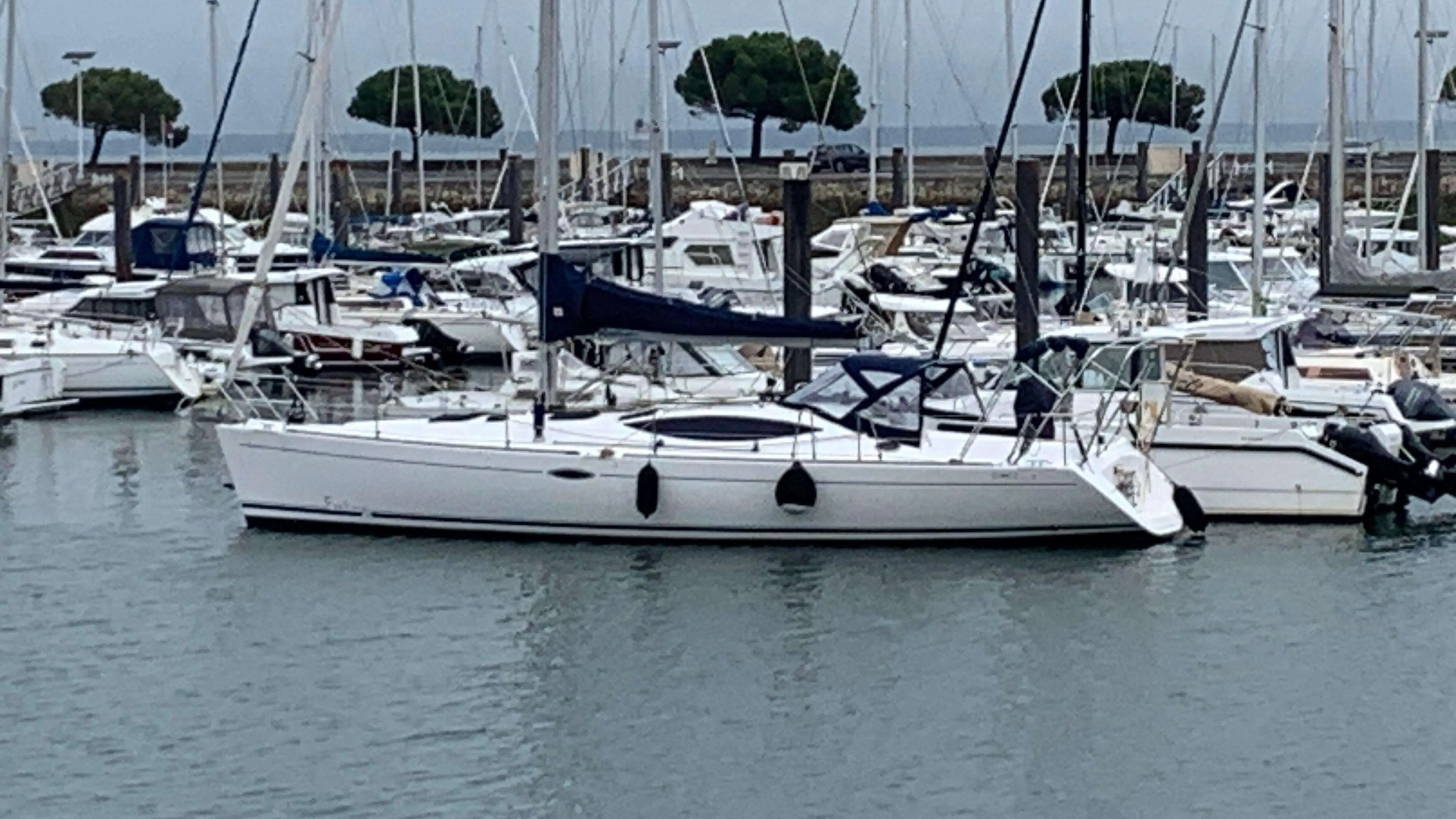 Kirie Feeling 44 — Voilier blanc vu de profil dans un port de plaisance, entouré d’autres bateaux.