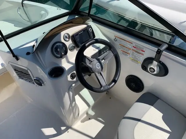 Bayliner E7 — Poste de pilotage avec volant, instruments, écran et siège du bateau.