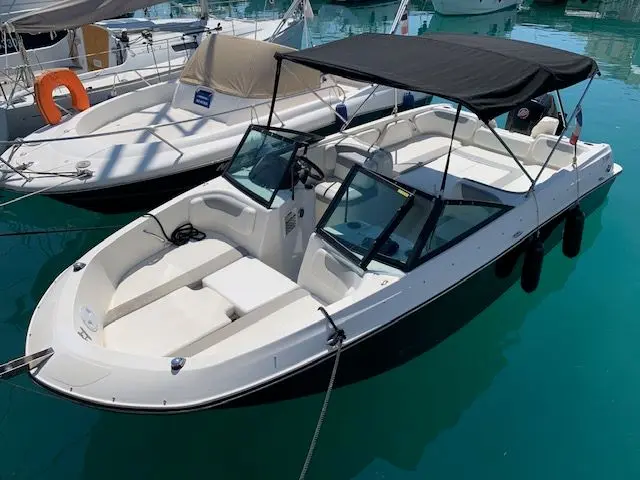 Bayliner E7 — Bateau à moteur blanc amarré dans une marina, vu de trois quarts avant.
