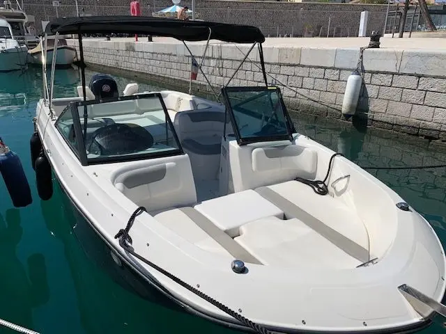 Bayliner E7 — Bateau à moteur blanc vu de trois quarts avant dans un port.