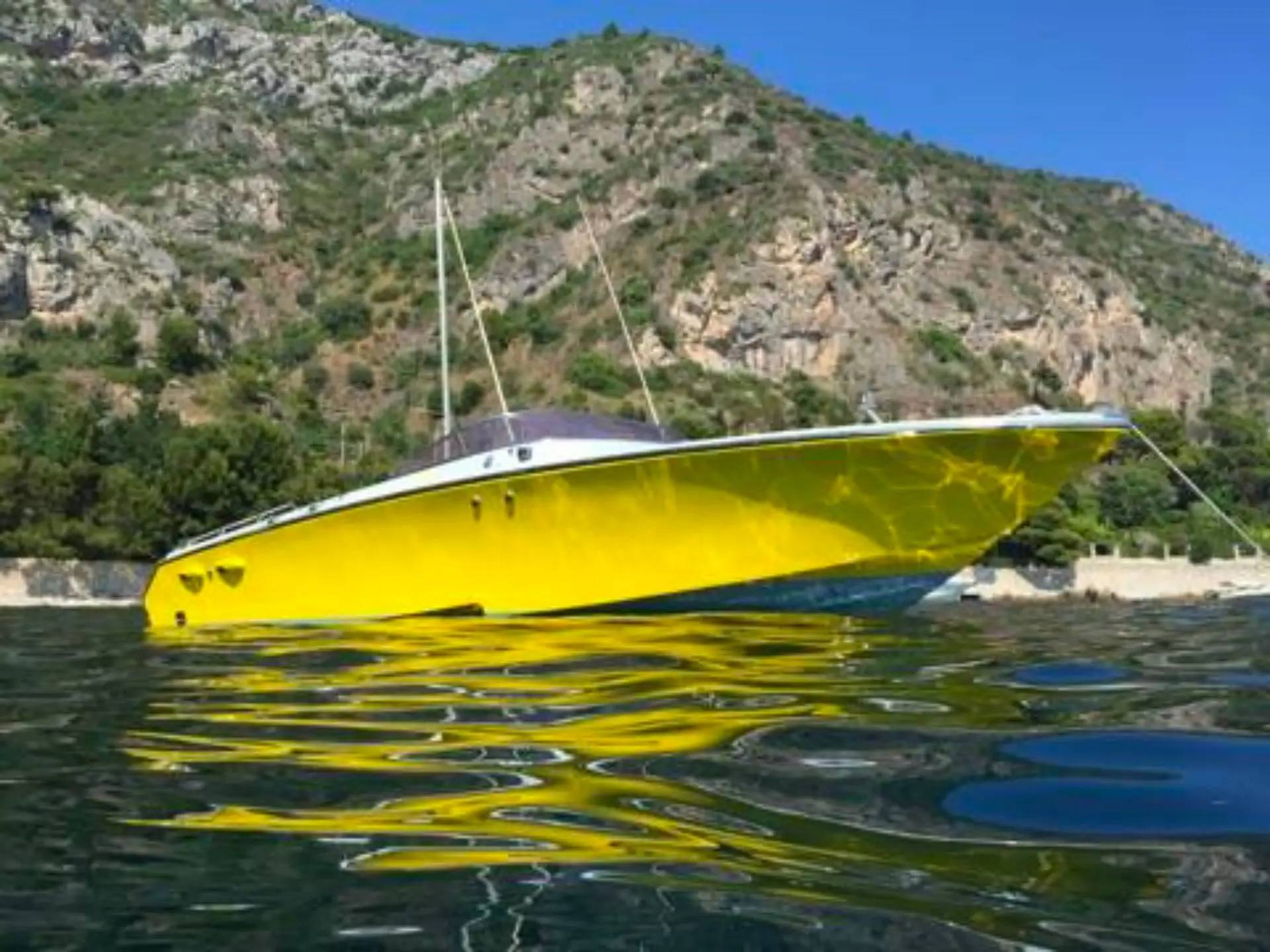 Offshore Marine Monte Carlo 30 — Bateau à moteur jaune photographié au mouillage devant une côte rocheuse.