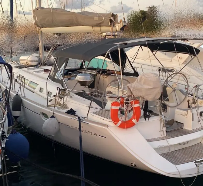 Jeanneau Sun Odyssey 49i — Voilier amarré au port, vu de trois quarts arrière parmi d'autres bateaux.