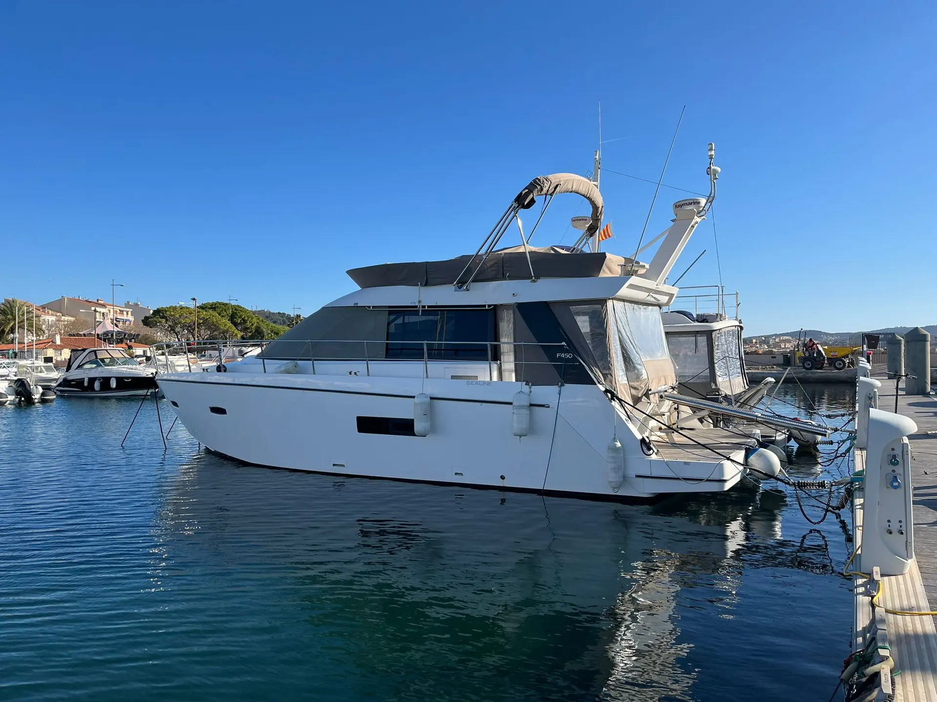 Sealine F 42 — Bateau à moteur blanc amarré dans un port, vu de trois quarts arrière.