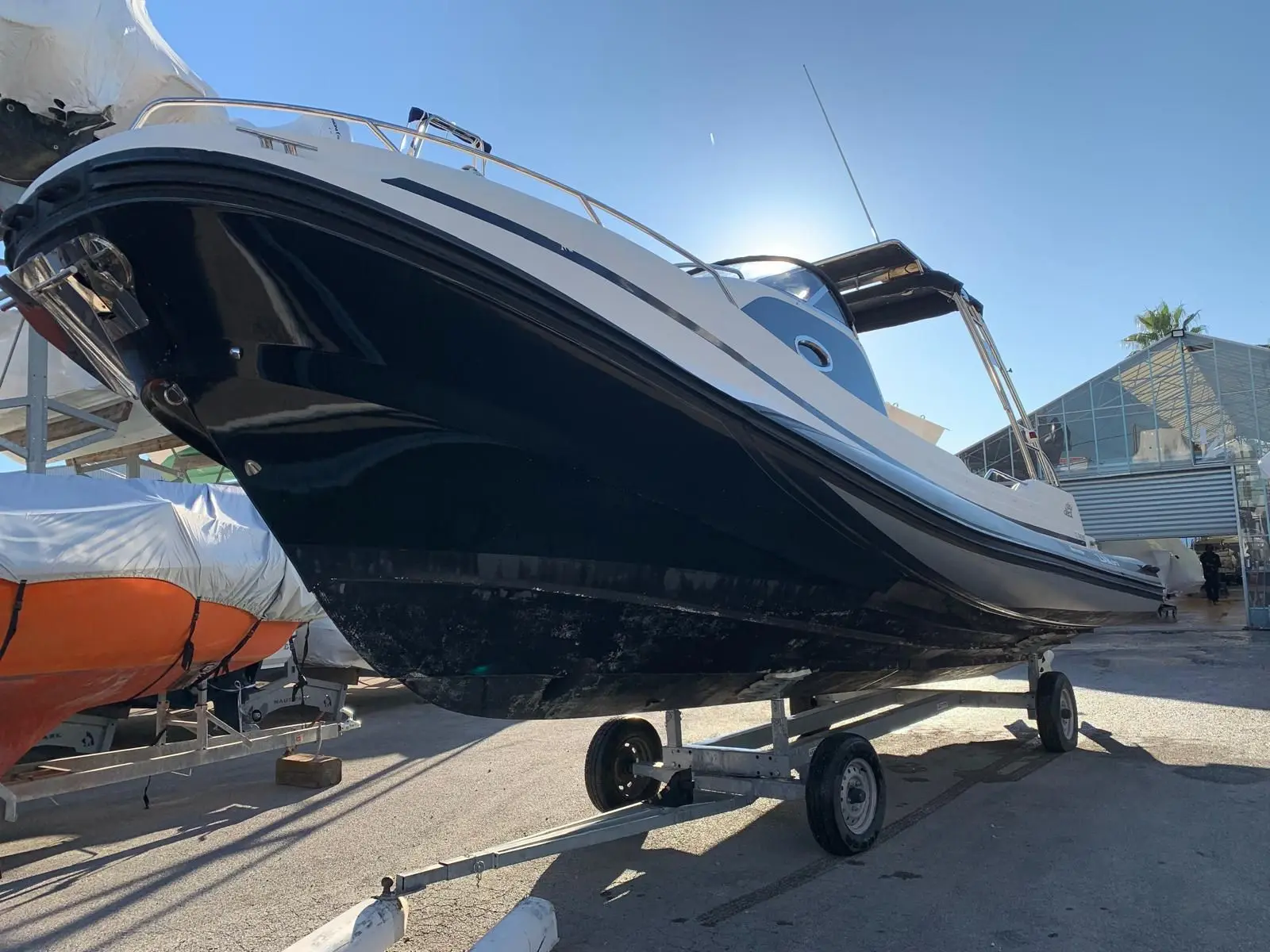 Zar Formenti Zar 97 Sky Deck — Bateau à moteur blanc et noir présenté sur une remorque dans une zone de stockage.