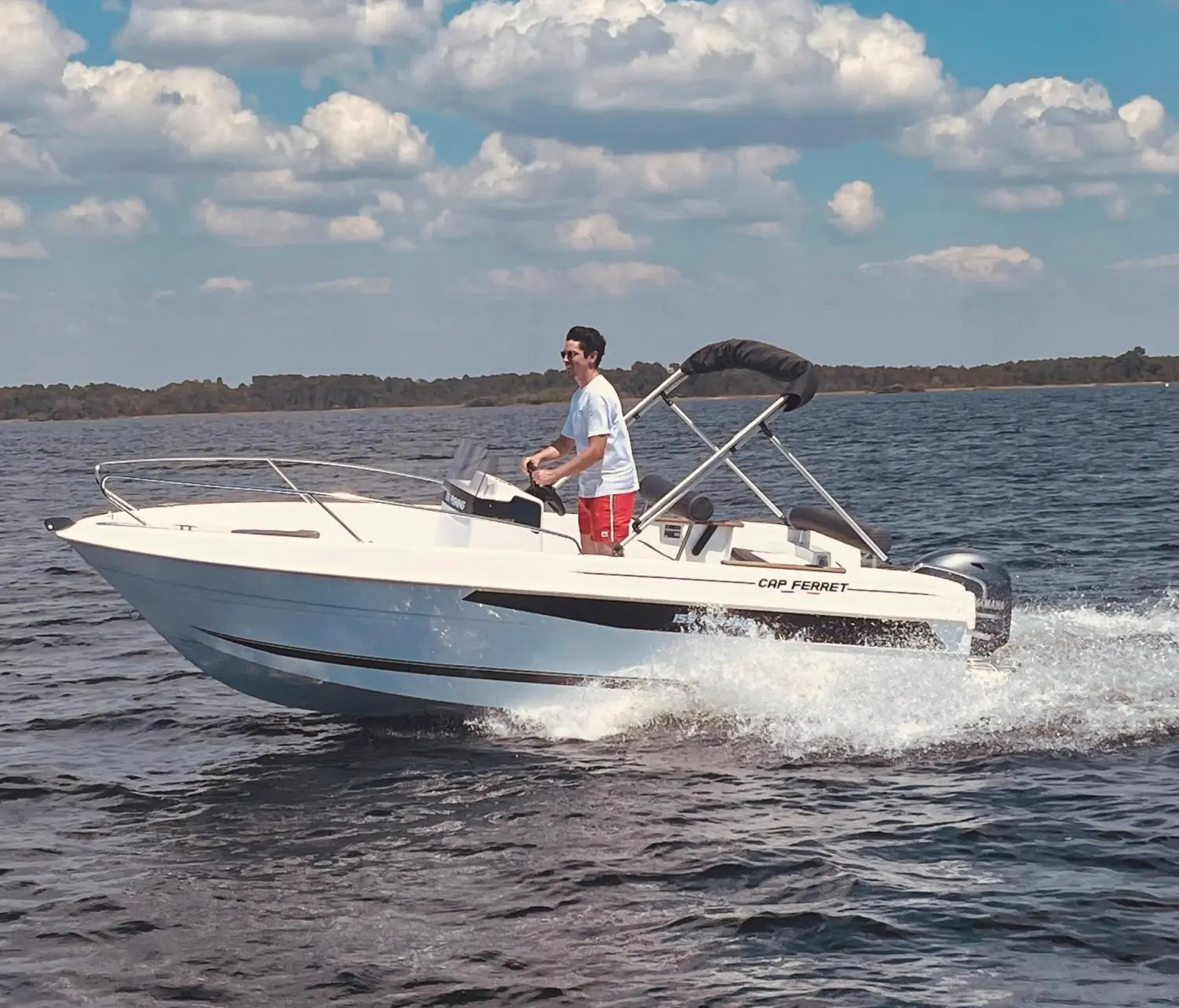 B2 Marine Cap Ferret 155 Fishing — Bateau à moteur blanc naviguant sur un plan d’eau avec une personne à la barre.
