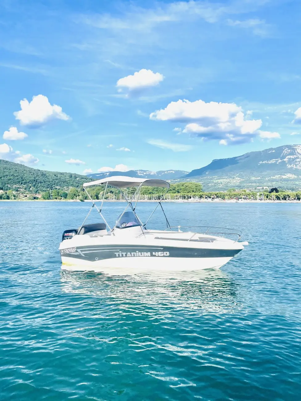 Titanium 460 Open — Bateau à moteur vu de profil sur un lac, avec taud et moteur hors-bord.