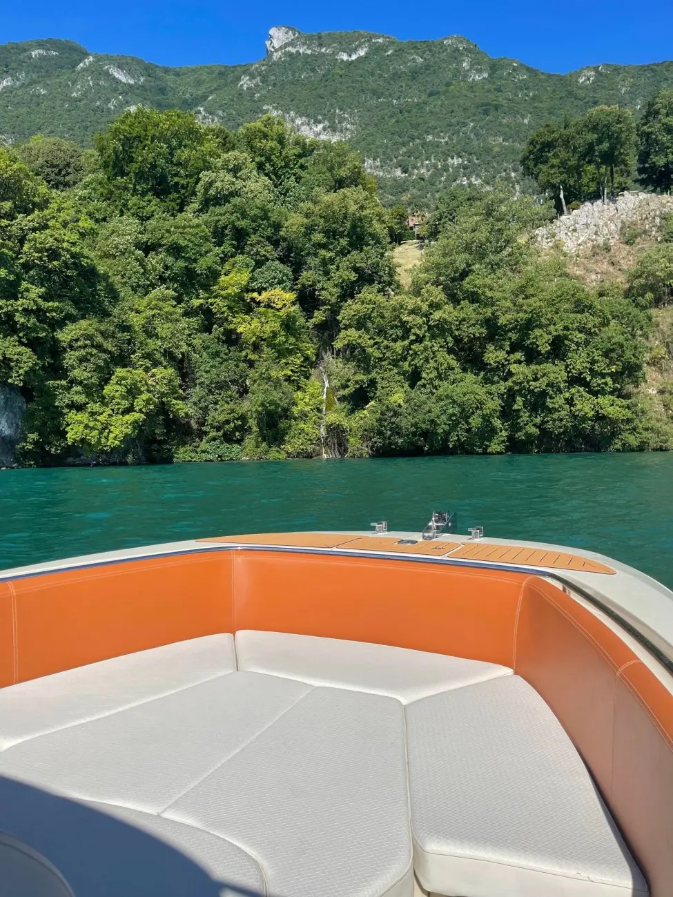 Invictus 200 FX — Vue de l'avant d'un bateau avec banquette blanche et habillage orange sur un lac.