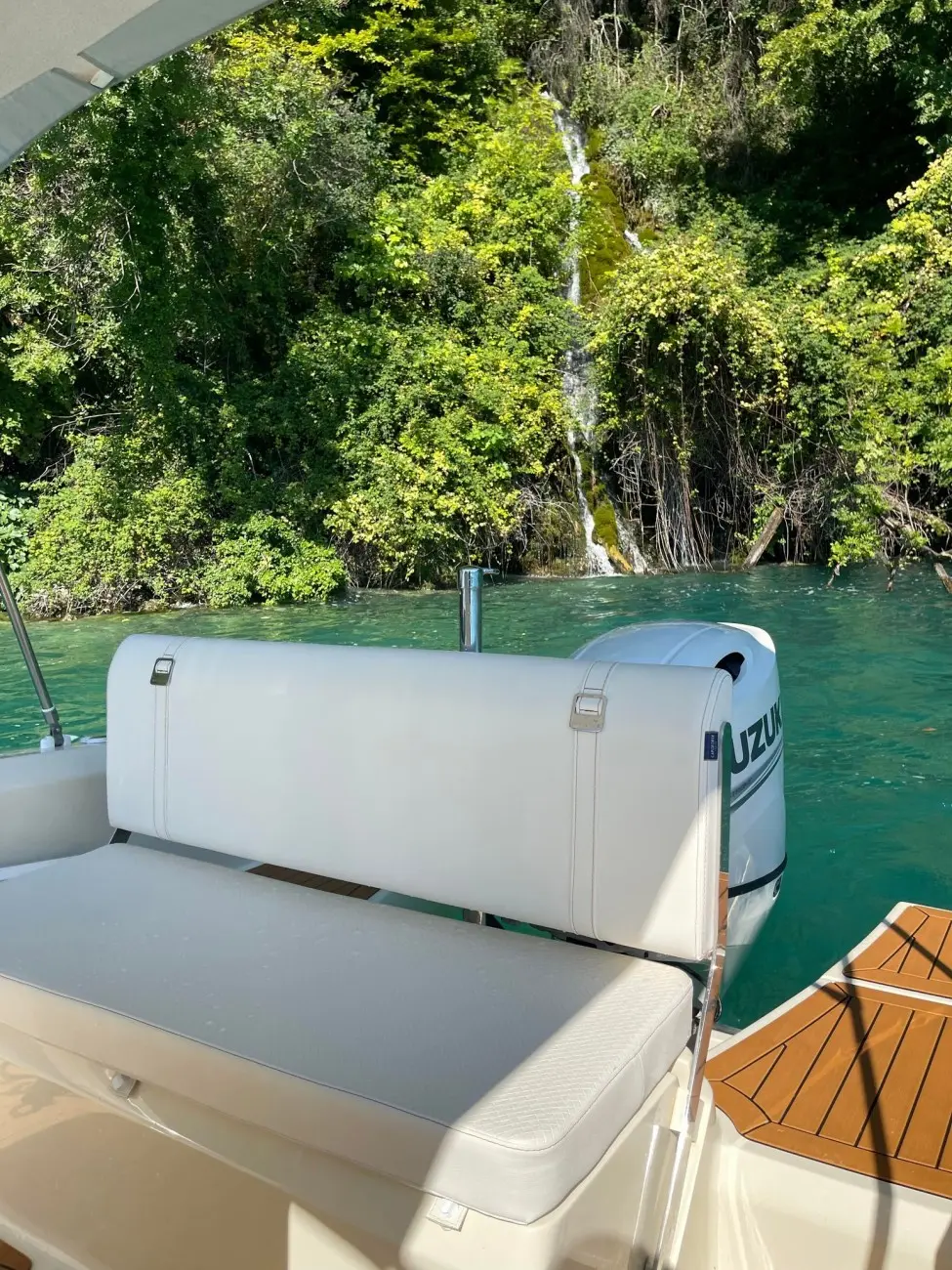 Invictus 200 FX — Vue partielle de l’arrière d’un bateau avec moteur hors-bord sur une eau turquoise.