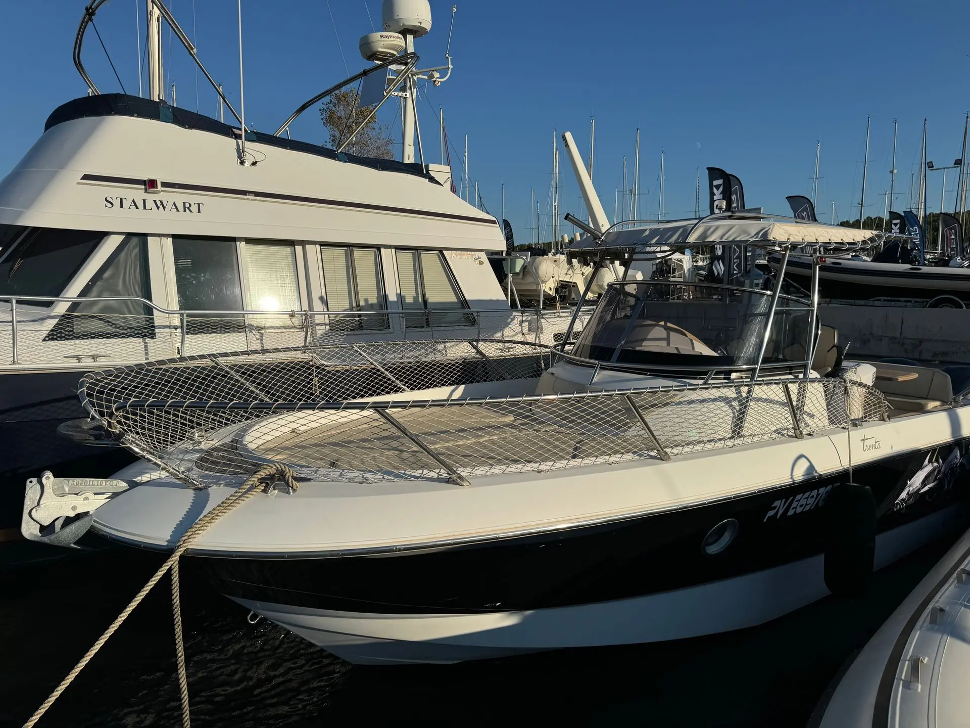 Sessa Marine Key Largo 30 — Bateau à moteur blanc et noir amarré dans un port, vu de trois quarts avant.