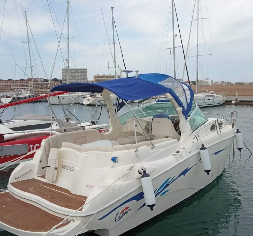 Lema Gold — Bateau à moteur blanc à toit bleu, amarré dans un port vu de trois quarts arrière.