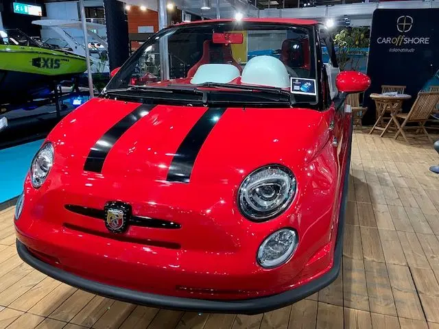Offshore Passion FIAT 500 ABARTH — Voiture rouge exposée sur un stand, avec un bateau vert visible à l’arrière-plan.