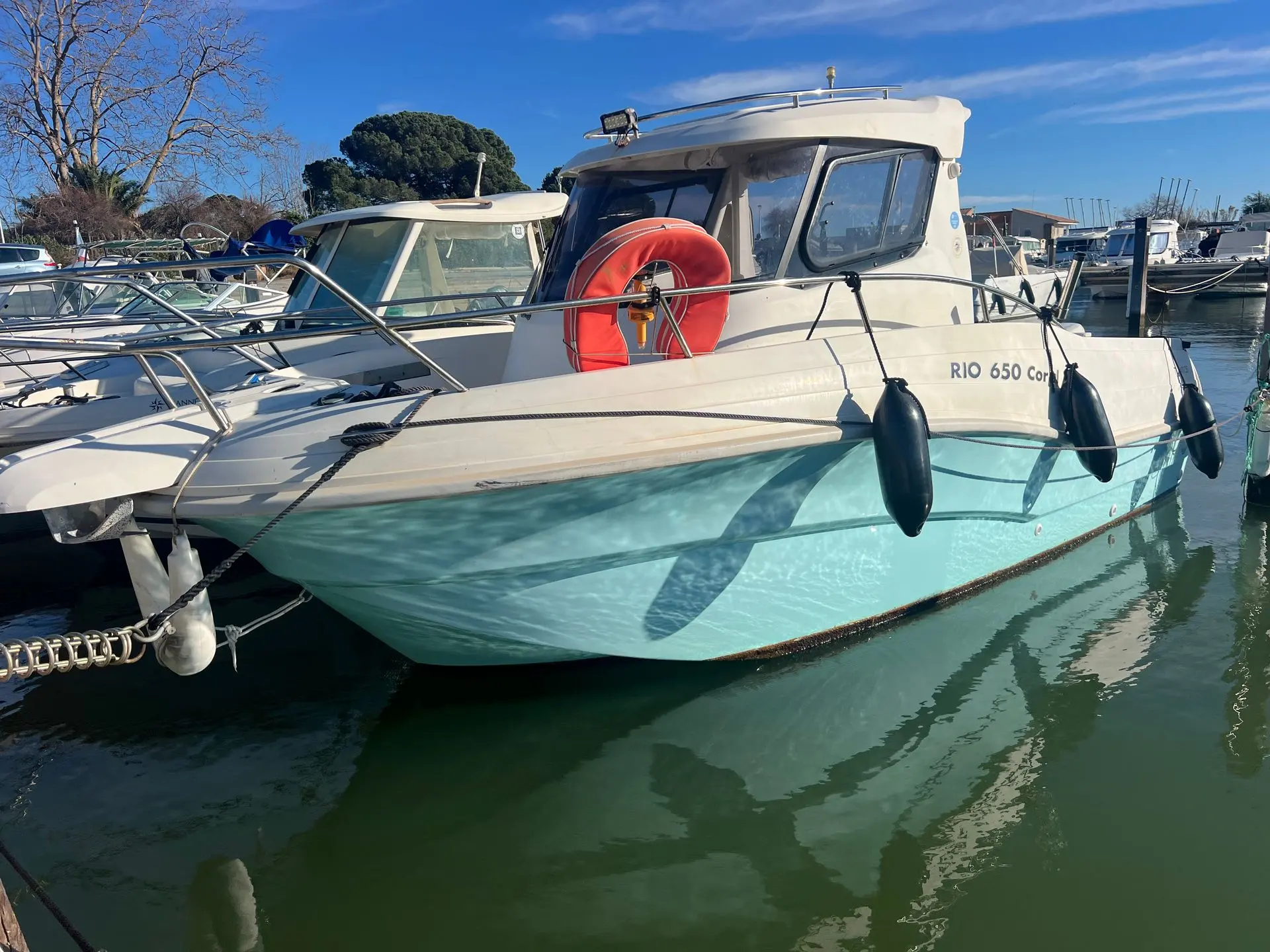 Rio 650 Coral — Bateau à cabine amarré dans un port, vu de trois quarts avant.