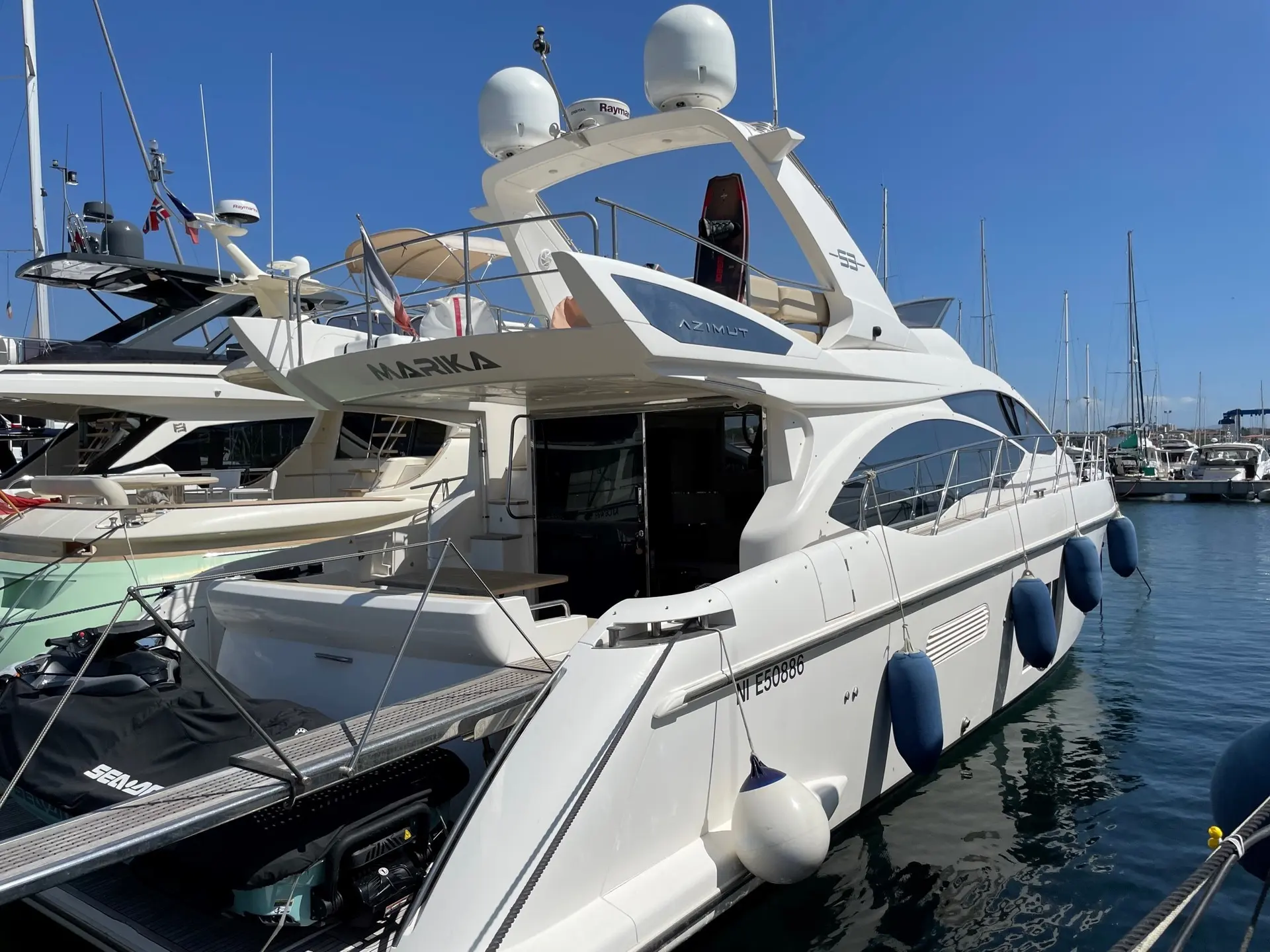 Azimut 53 — Bateau à moteur blanc amarré dans une marina, vu de trois quarts arrière.