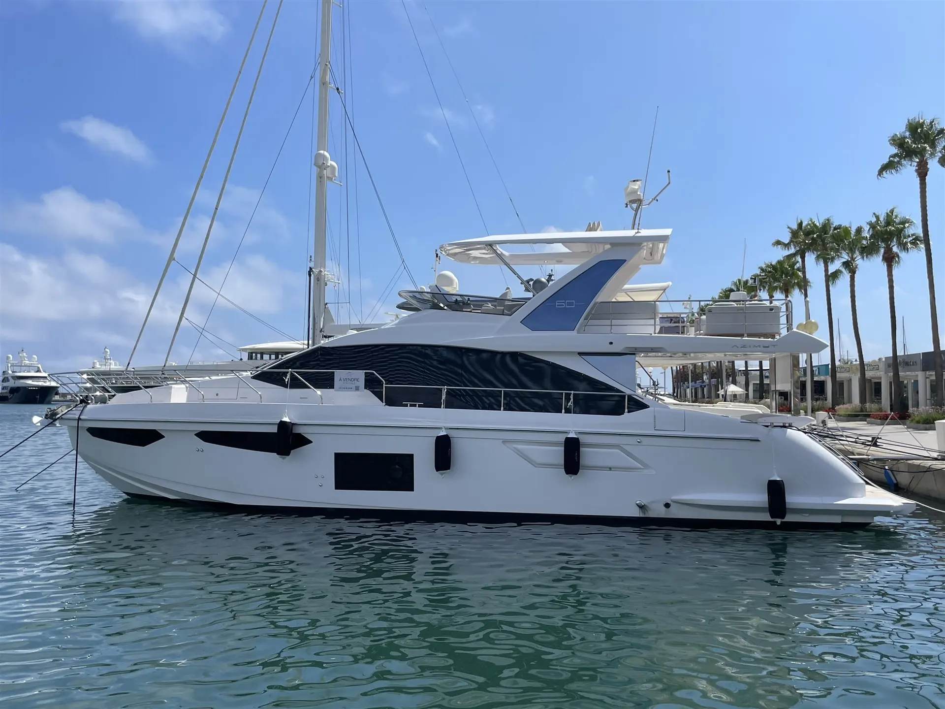 Azimut 60 Fly — Vue latérale d’un yacht à moteur blanc amarré dans une marina.