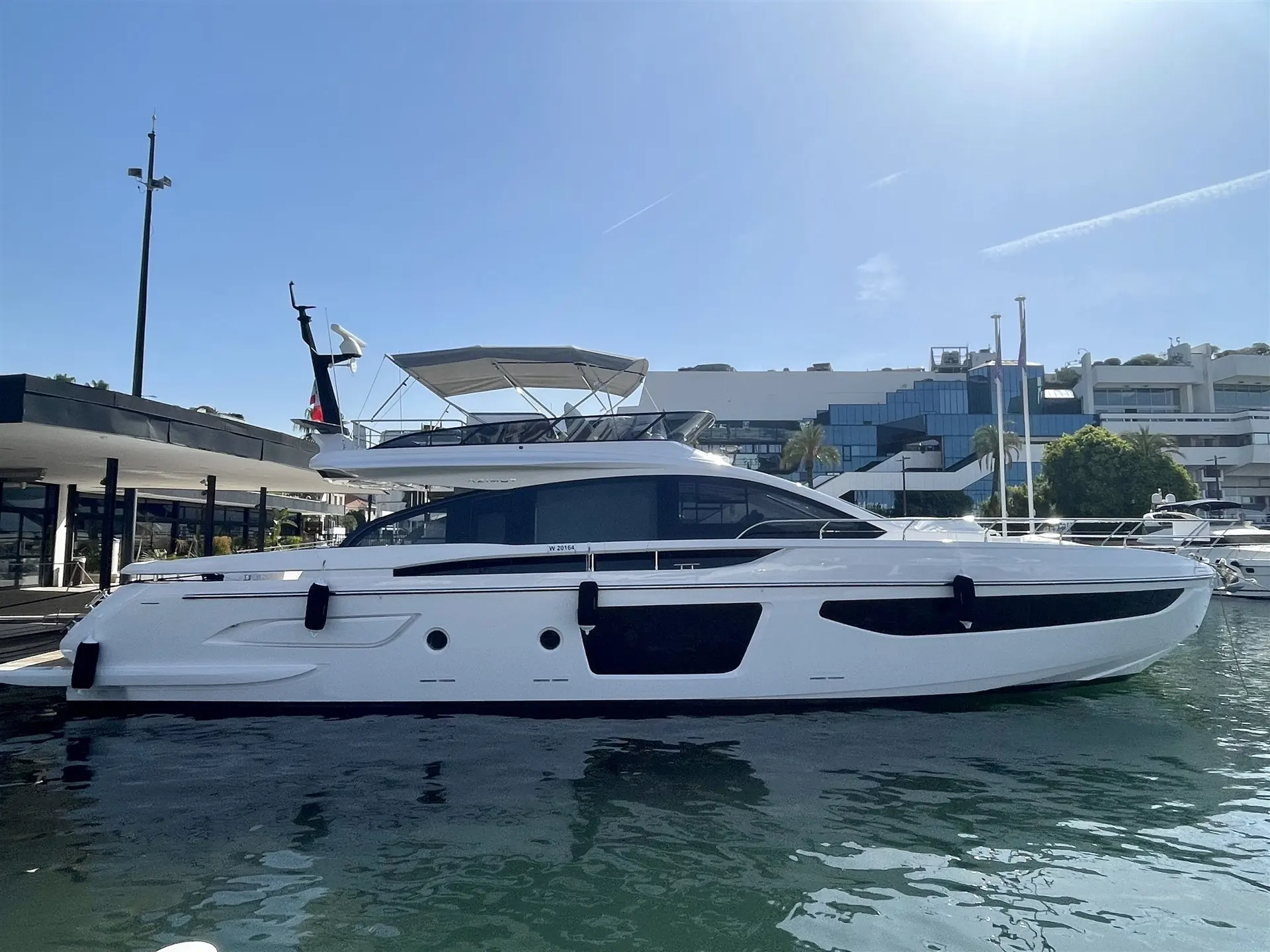 Azimut S7 — Bateau à moteur blanc vu de profil, amarré dans une marina par temps ensoleillé.