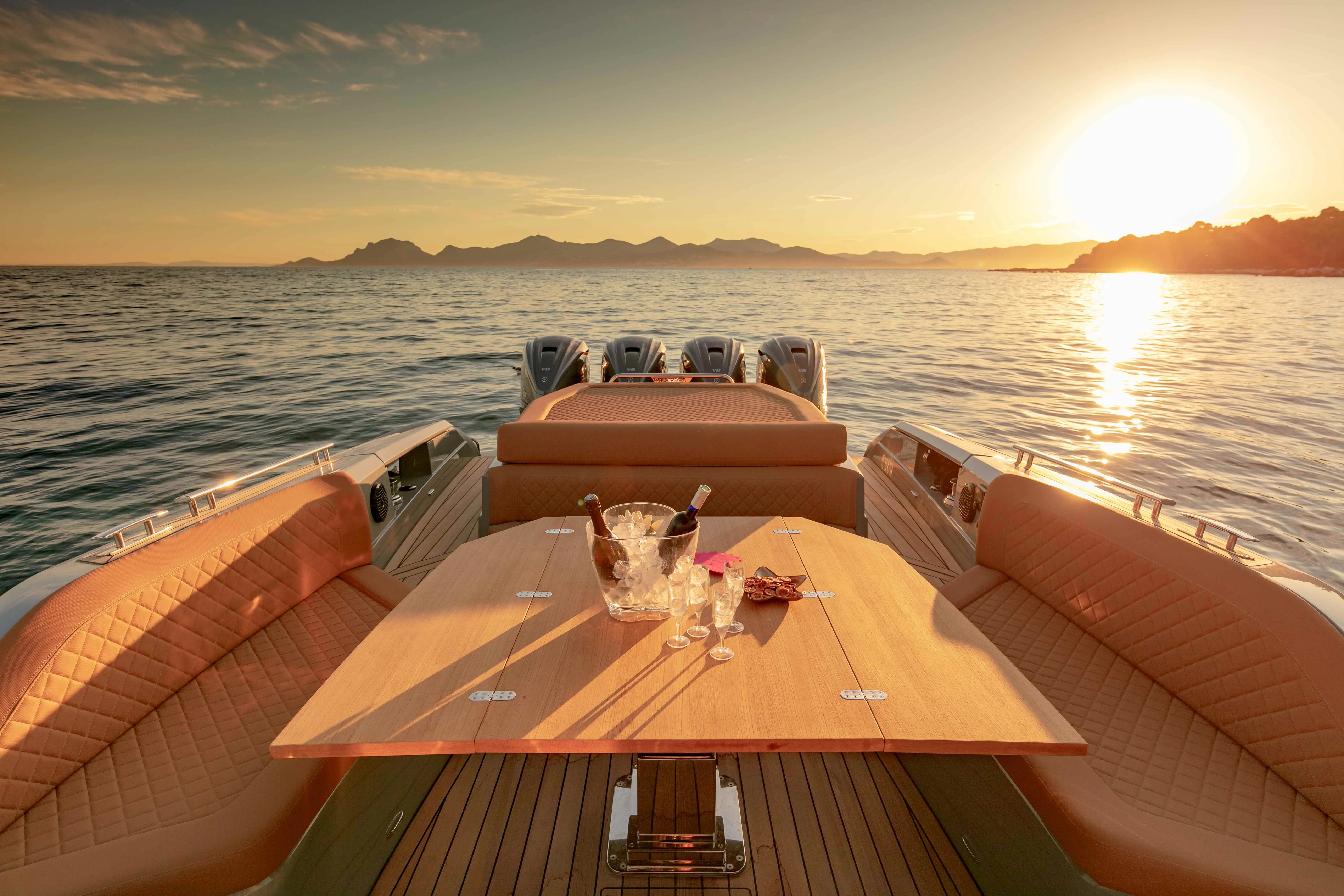 Nuova Jolly Prince 50 — Vue arrière du cockpit avec banquettes, table et quatre moteurs hors-bord au coucher du soleil.