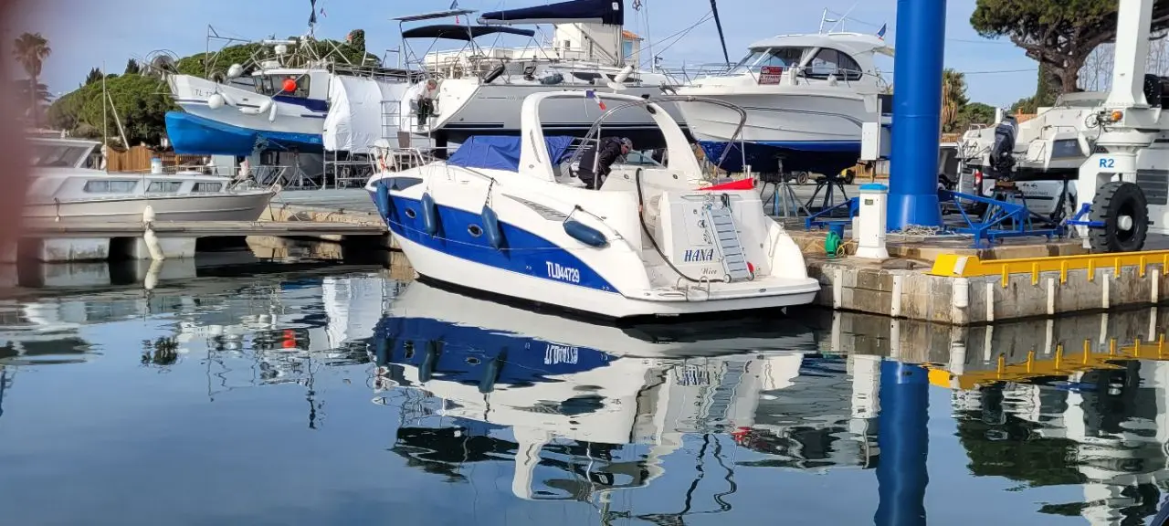 Bayliner 325 — Bateau à moteur blanc et bleu amarré dans une marina, vu de trois quarts arrière.