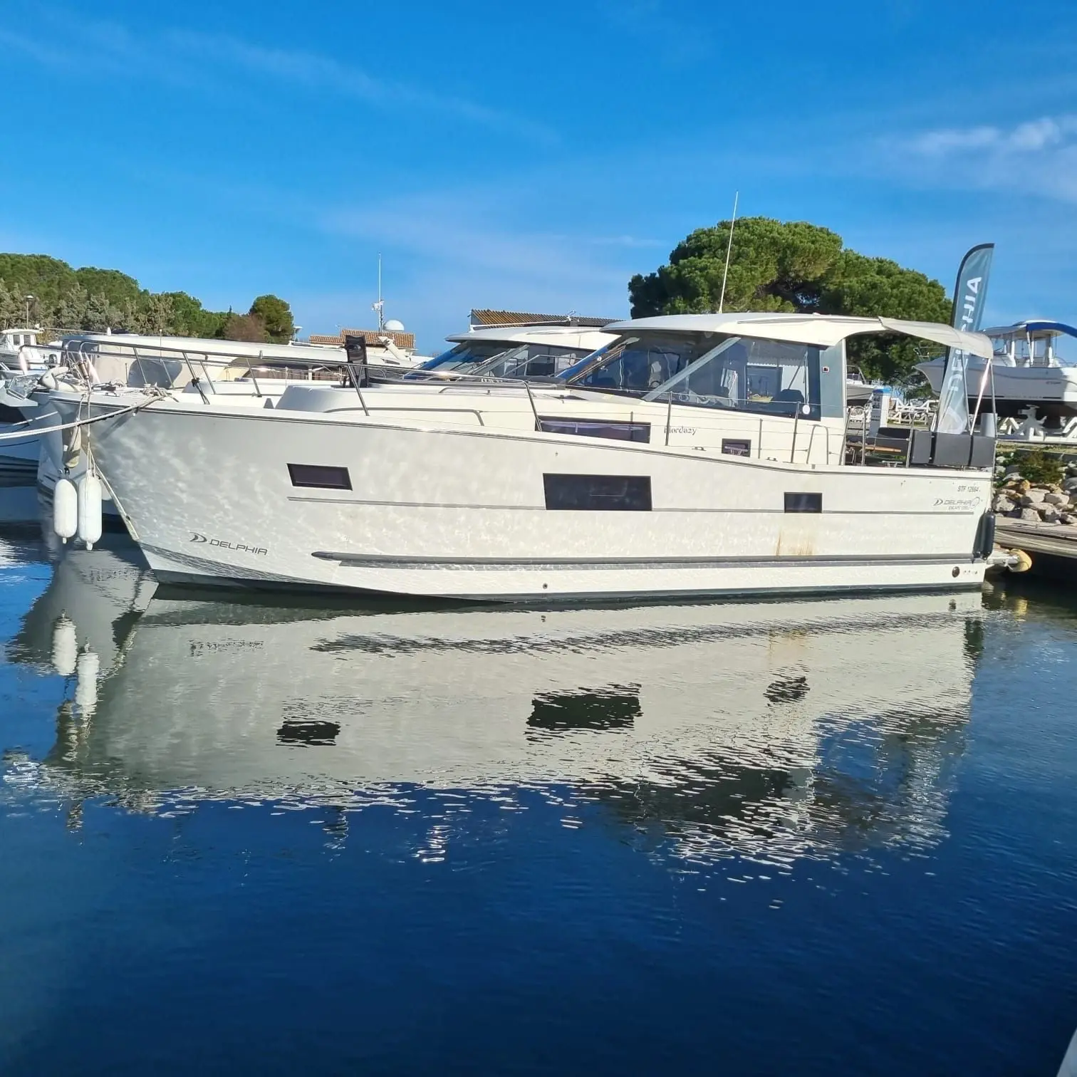 Delphia 1080 Soley — Bateau à moteur blanc amarré, photographié de profil dans un port.