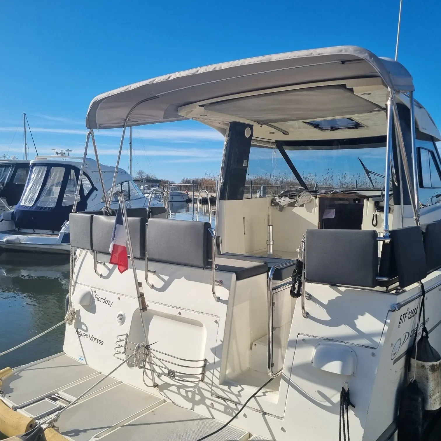 Delphia 1080 Soley — Vue arrière du cockpit et de la cabine d’un bateau amarré au port.