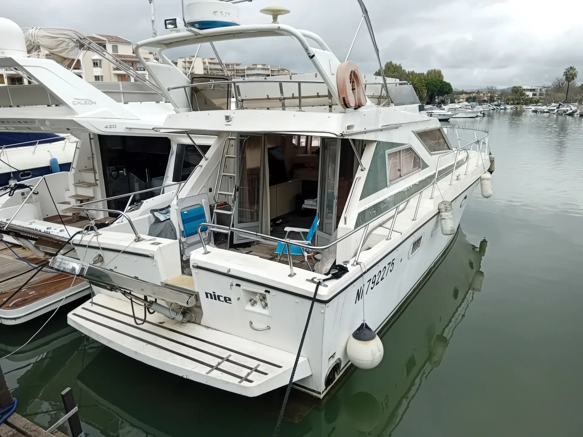 Guy Couach 1201 — Vedette à moteur blanche amarrée dans un port, vue de trois quarts arrière.