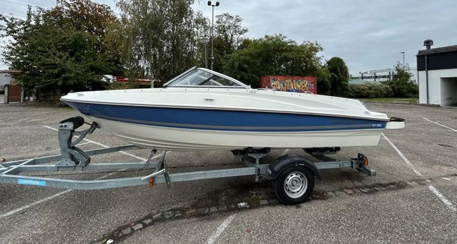 Bayliner 185 — Bateau à moteur blanc et bleu présenté sur sa remorque dans un parking.