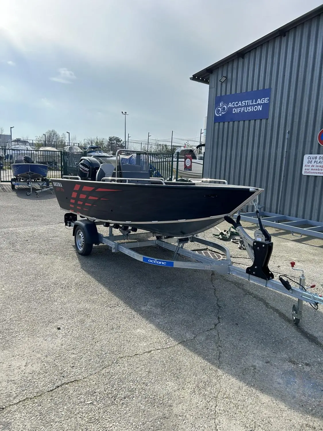 Brema 480v Pro — Bateau à moteur noir posé sur une remorque devant un bâtiment nautique.