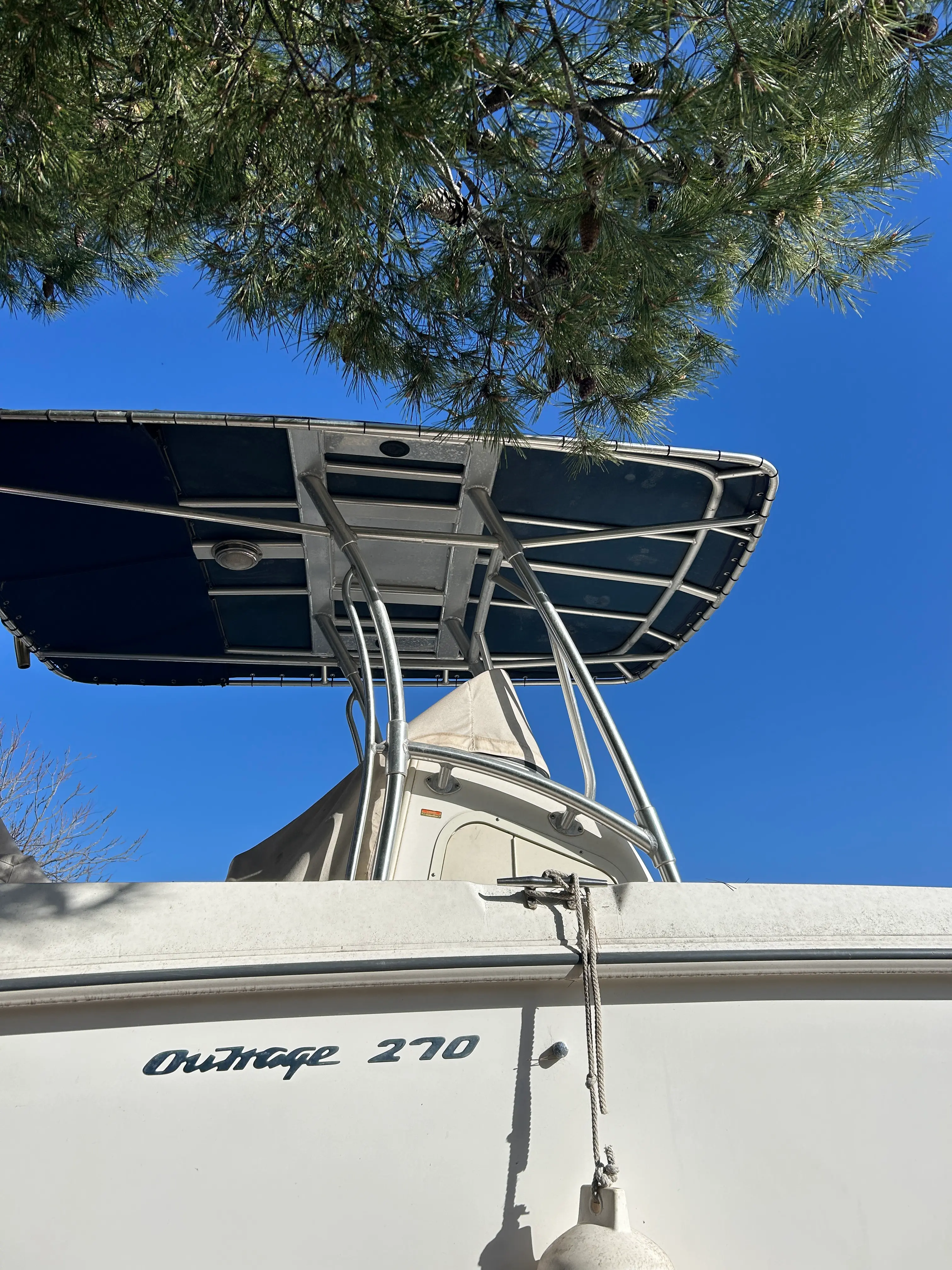 Boston Whaler 270 Outrage — Vue en contre-plongée d’un bateau blanc avec un taud et une structure métallique.