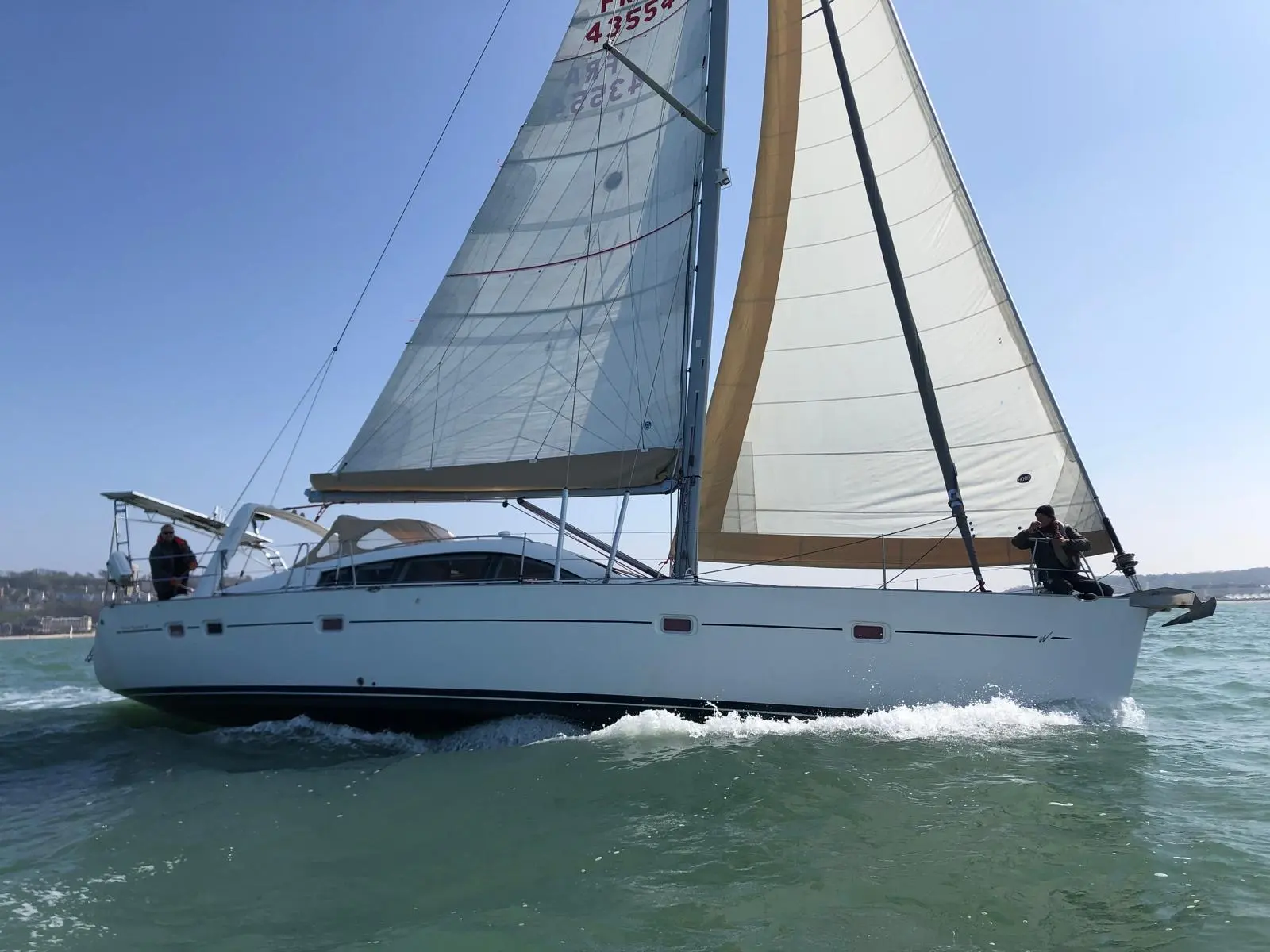 Wauquiez Pilot Saloon 47 — Voilier blanc naviguant sous voile, photographié de profil sur une mer agitée.