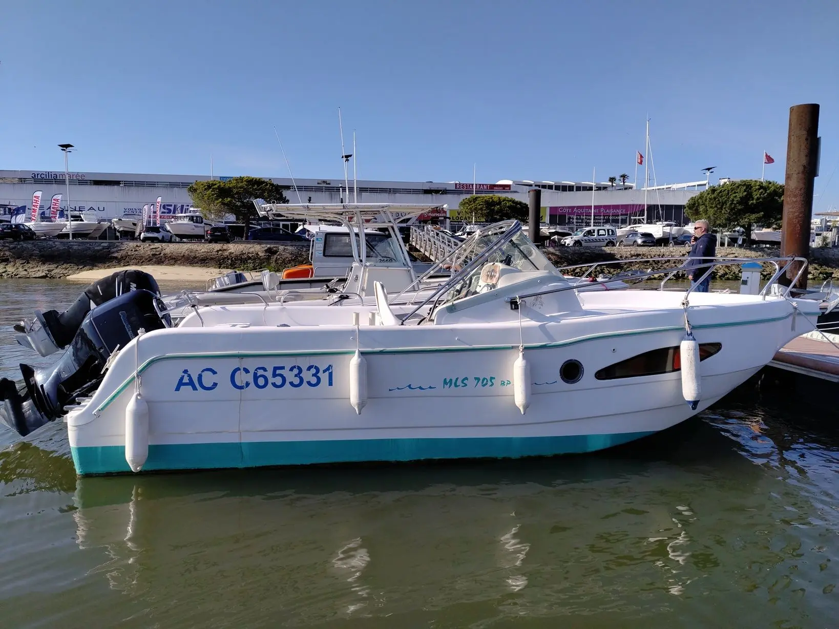 MLS 705 BP — Bateau à moteur blanc vu de profil, amarré dans une marina.