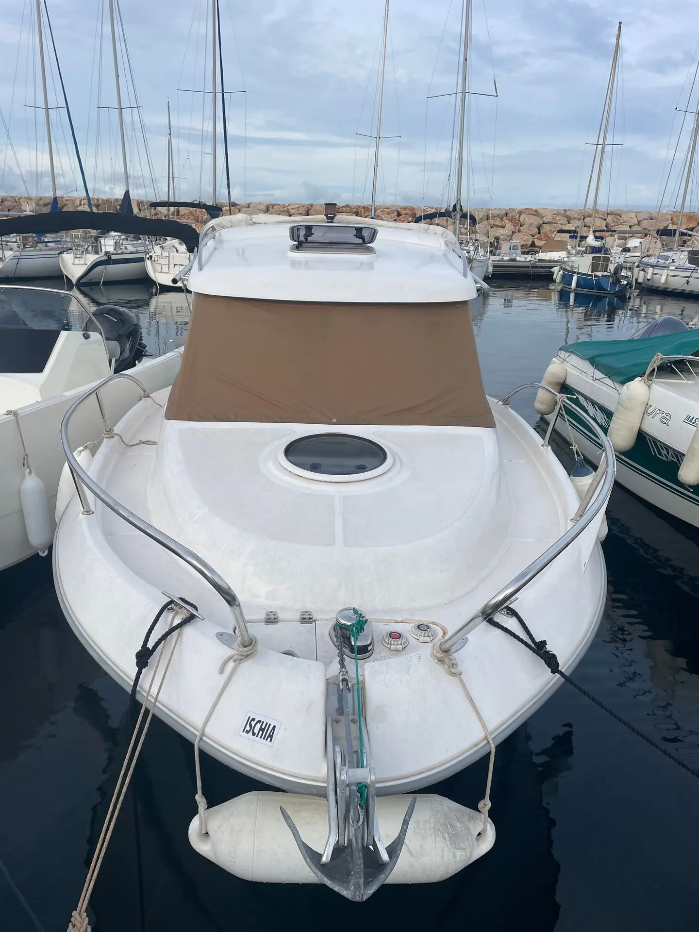 Sessa Marine Dorado 22 — Vue avant d’un bateau blanc amarré dans un port, avec taud beige et ancre.