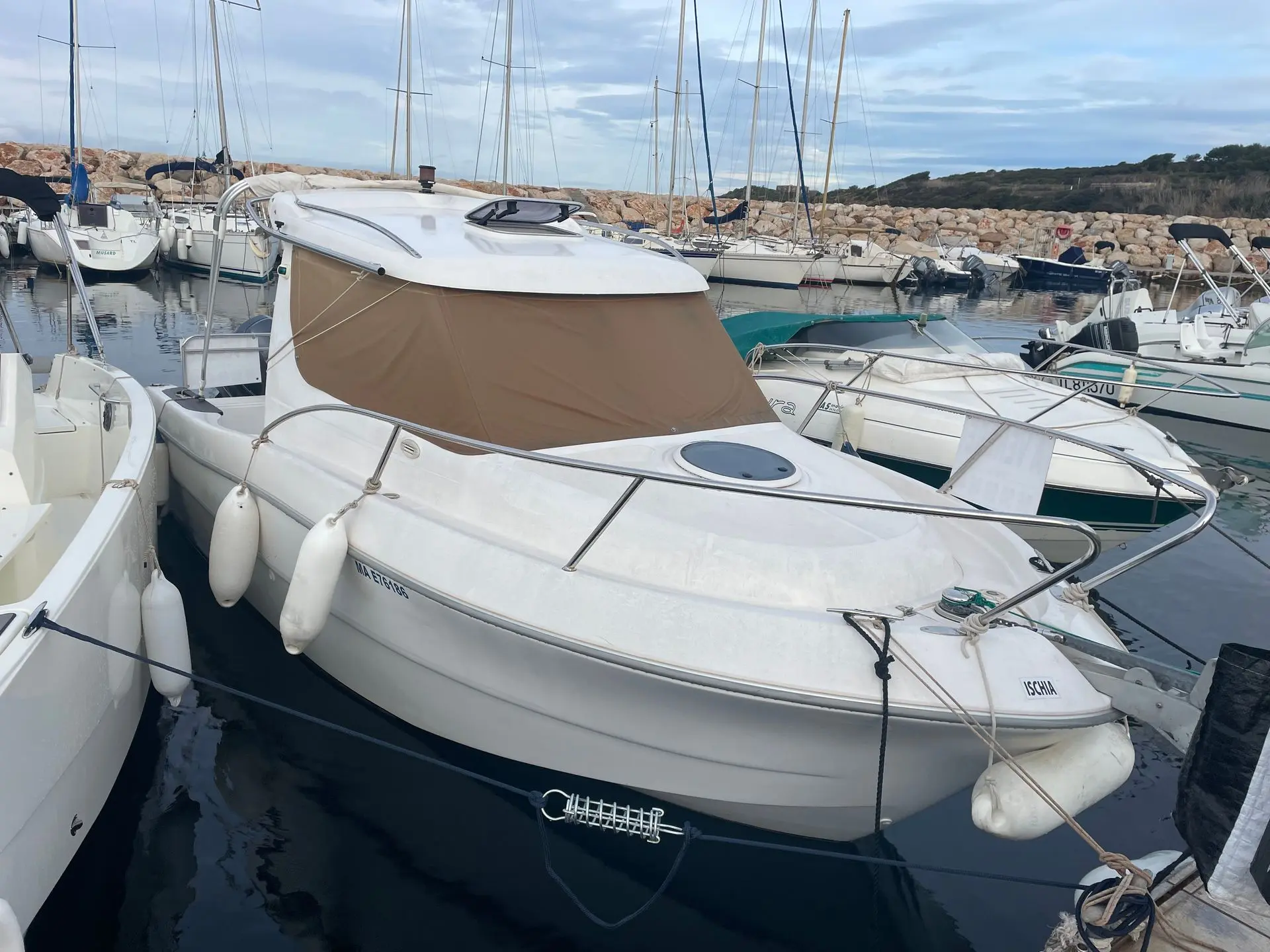 Sessa Marine Dorado 22 — Bateau à moteur blanc amarré dans un port, avec taud beige et pare-brise.
