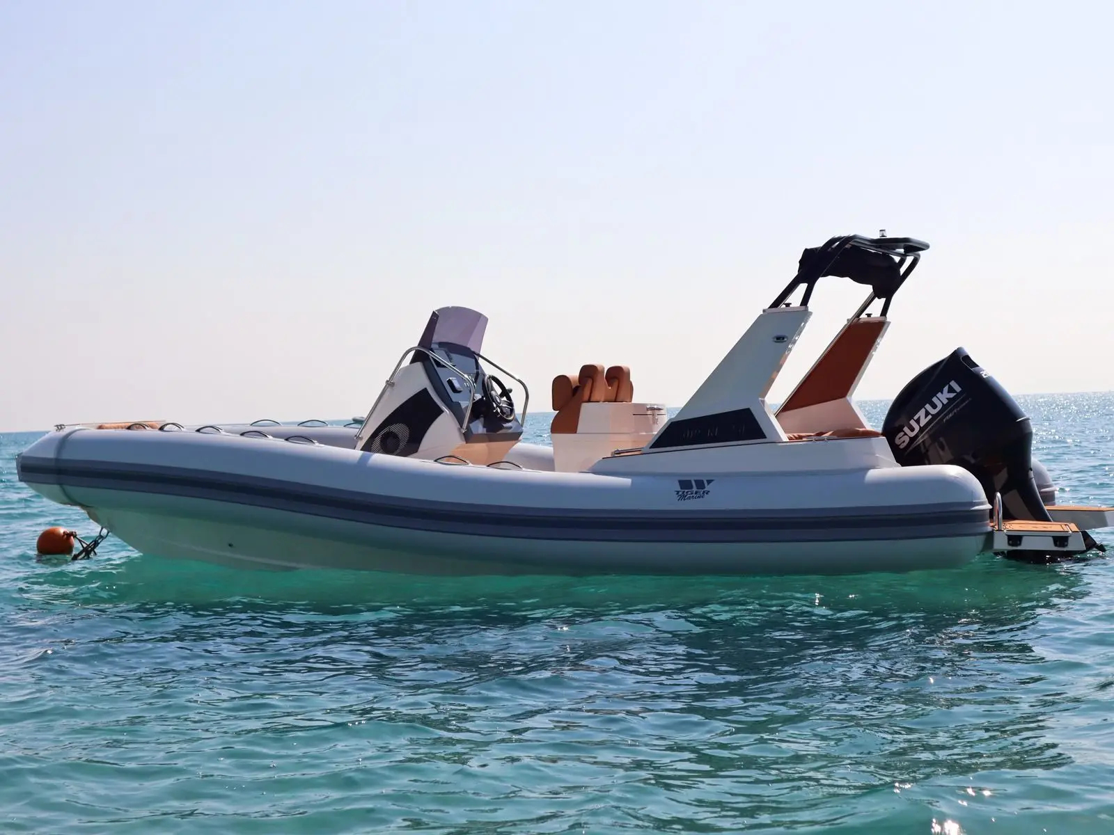 Tiger Marine 750 TOP LINE — Bateau semi-rigide vu de profil sur l’eau, avec console centrale et moteur hors-bord.