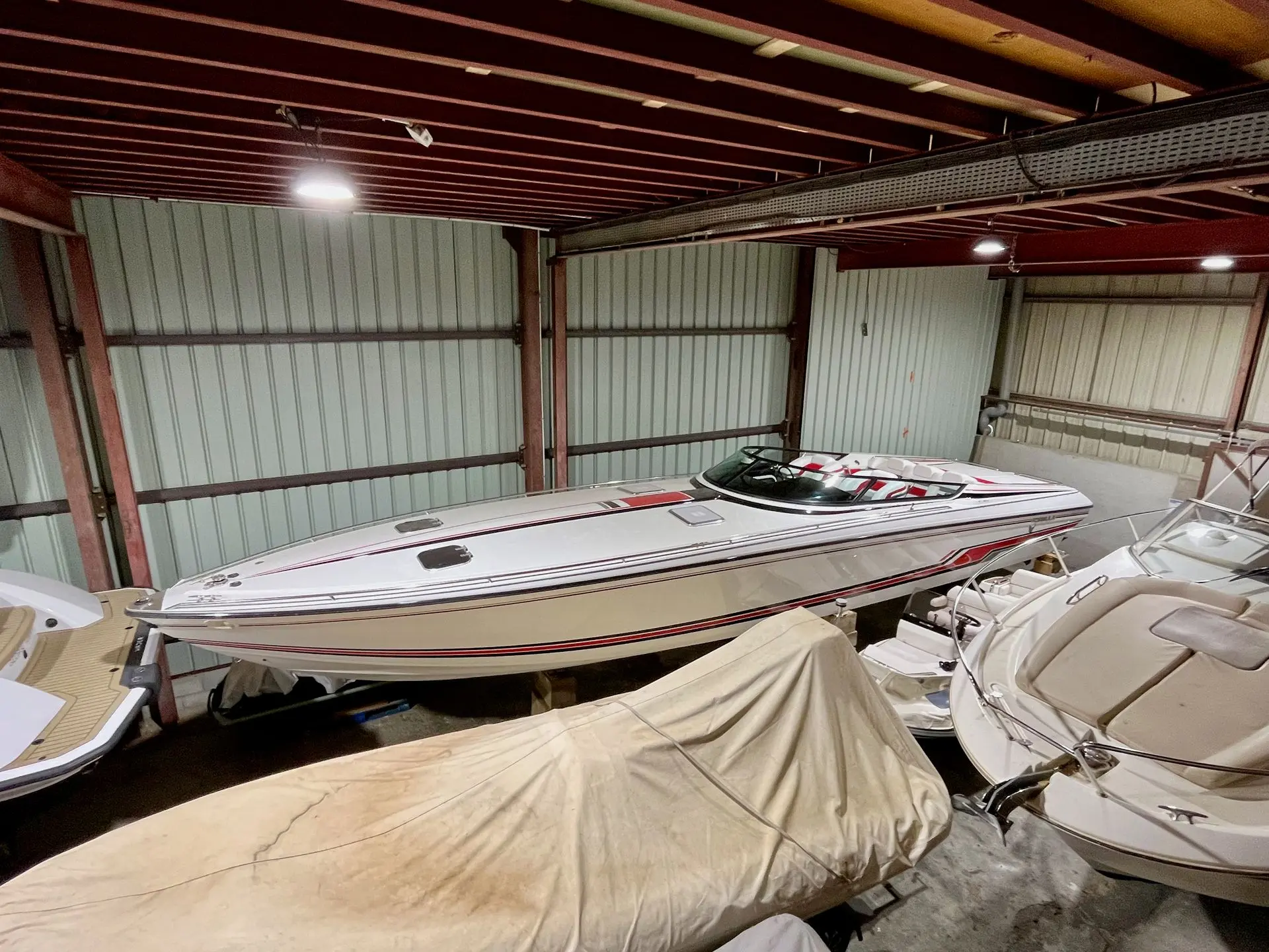 Formula 419 SRI — Vedette blanche à bandes rouges photographiée dans un hangar, entourée d’autres bateaux.