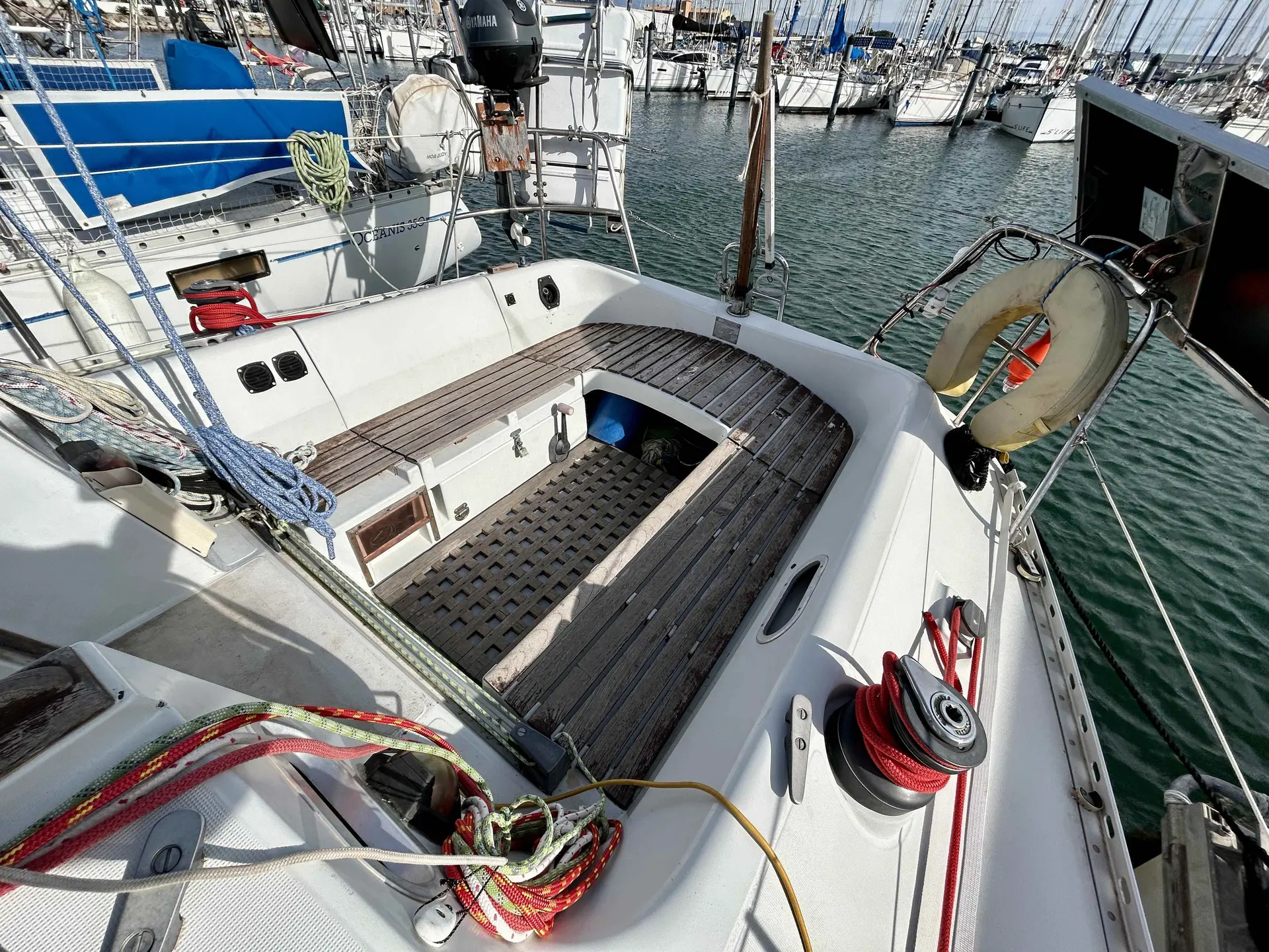 Kirie Feeling 960 — Cockpit arrière d’un voilier amarré, avec winch, gréement et moteur hors-bord visibles.
