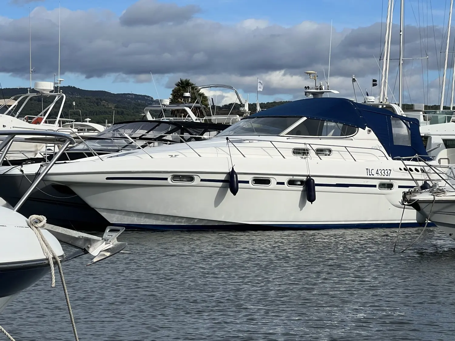 Sealine Ambassador 380 — Bateau à moteur blanc vu de profil dans un port, entouré d'autres embarcations.