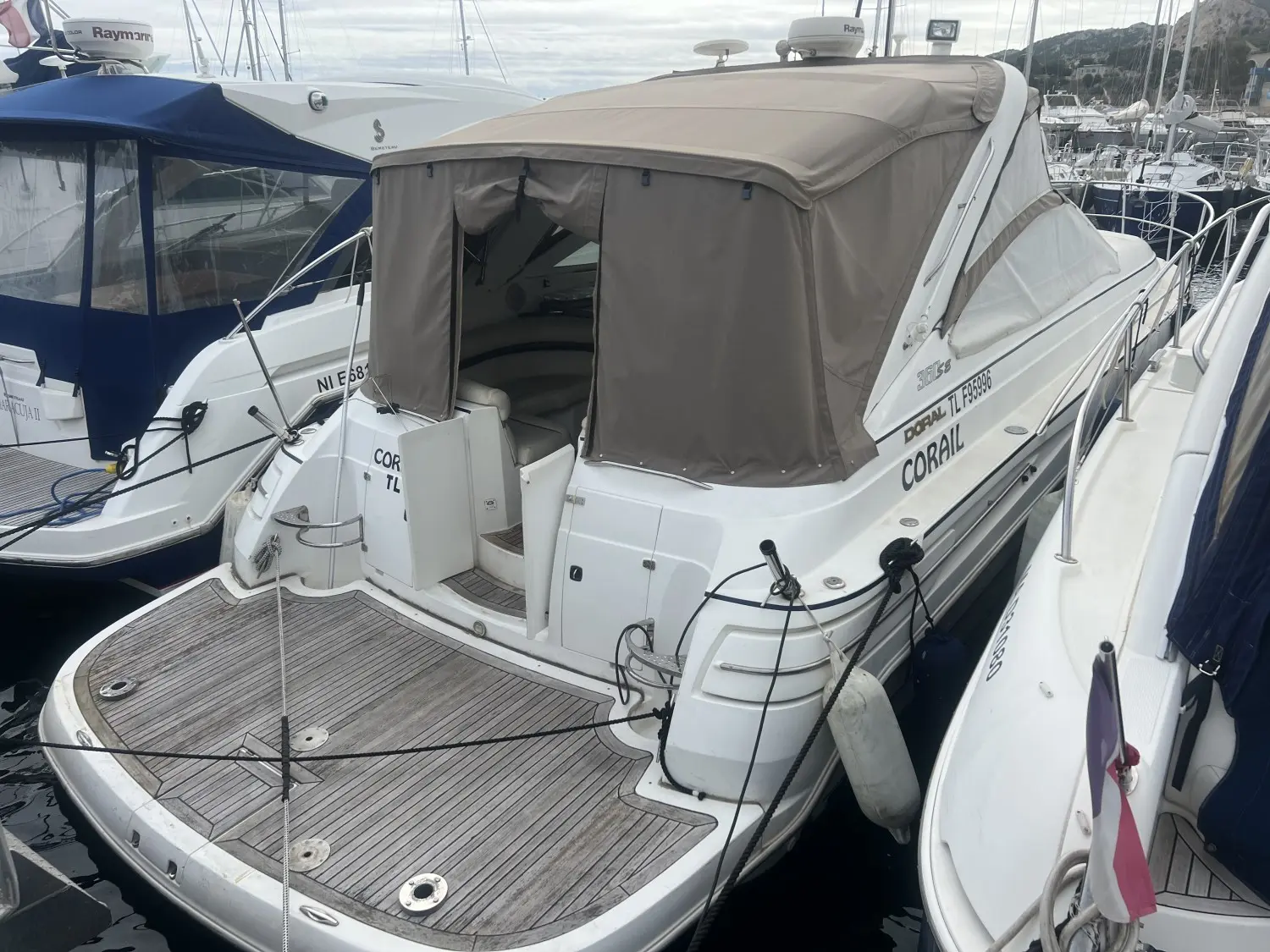 Doral 360 SE — Vue arrière trois-quarts d’un bateau blanc amarré, avec taud beige et plage arrière en teck.