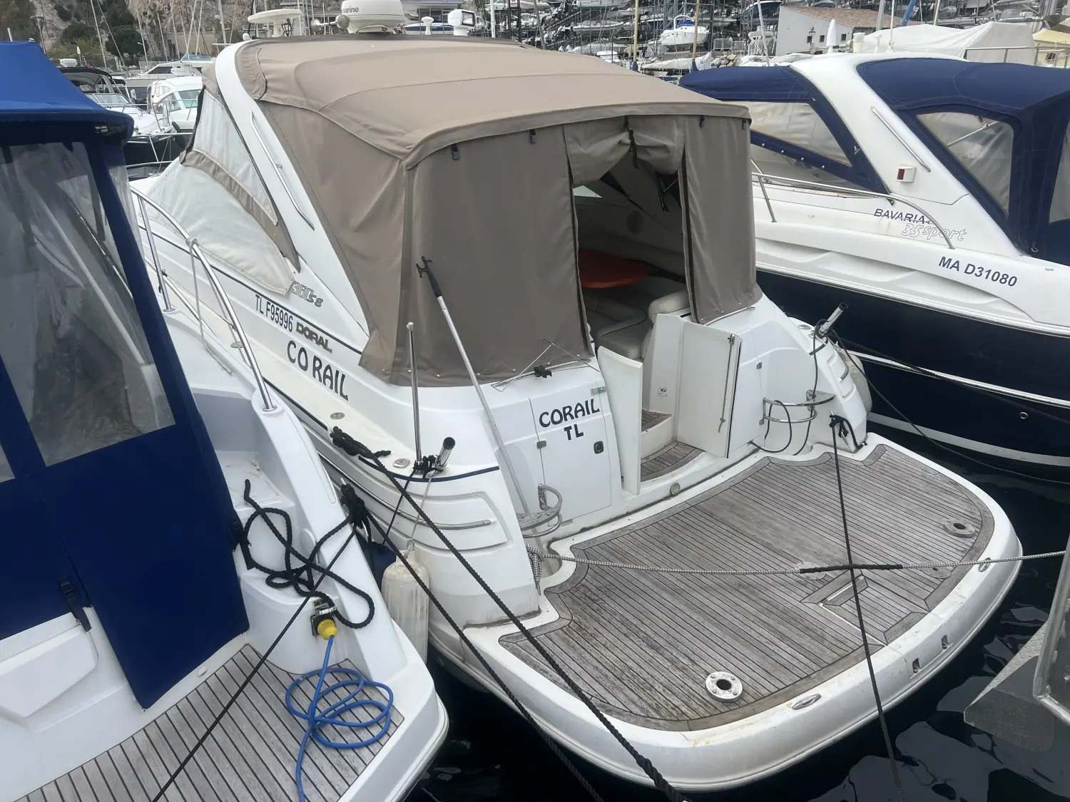 Doral 360 SE — Vue arrière trois-quarts d’un bateau blanc amarré, avec taud beige et plage arrière en teck.