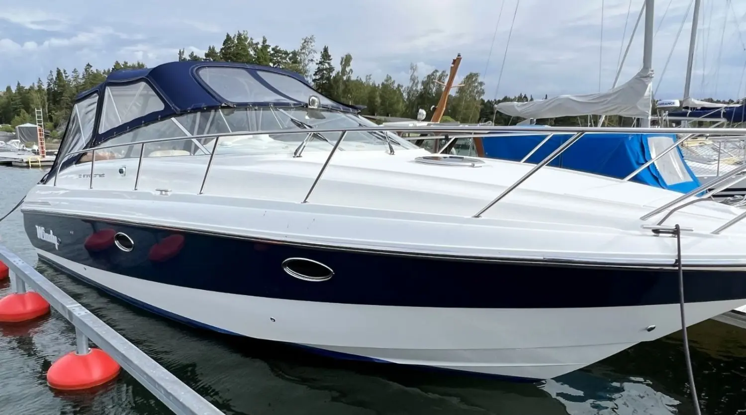 Windy 32 Grand Tornado — Bateau à moteur blanc et bleu amarré dans une marina, vu de profil.