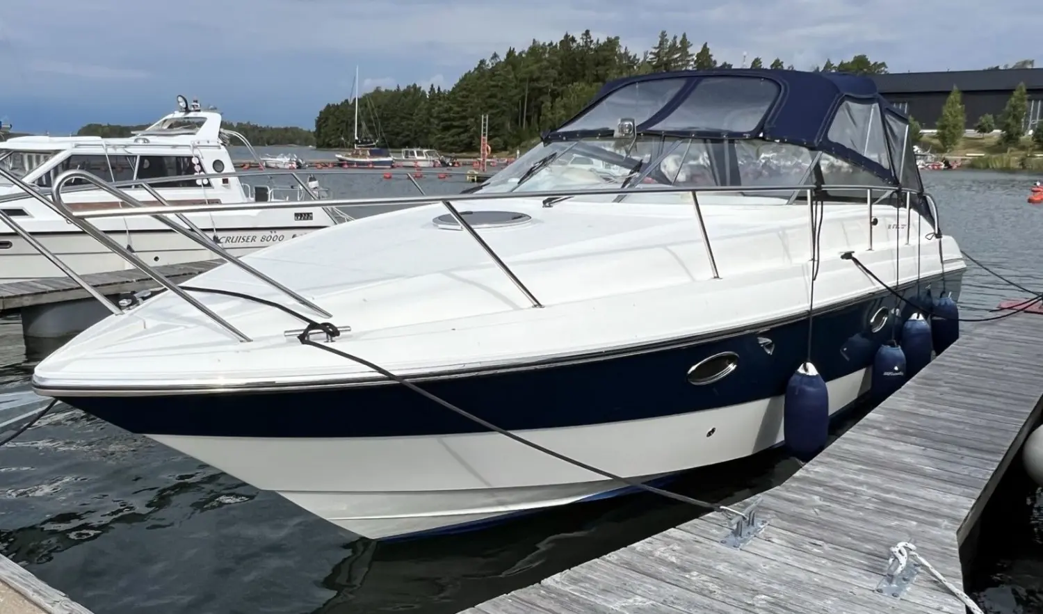 Windy 32 Grand Tornado — Bateau à moteur blanc et bleu amarré à un ponton, vu de trois quarts.