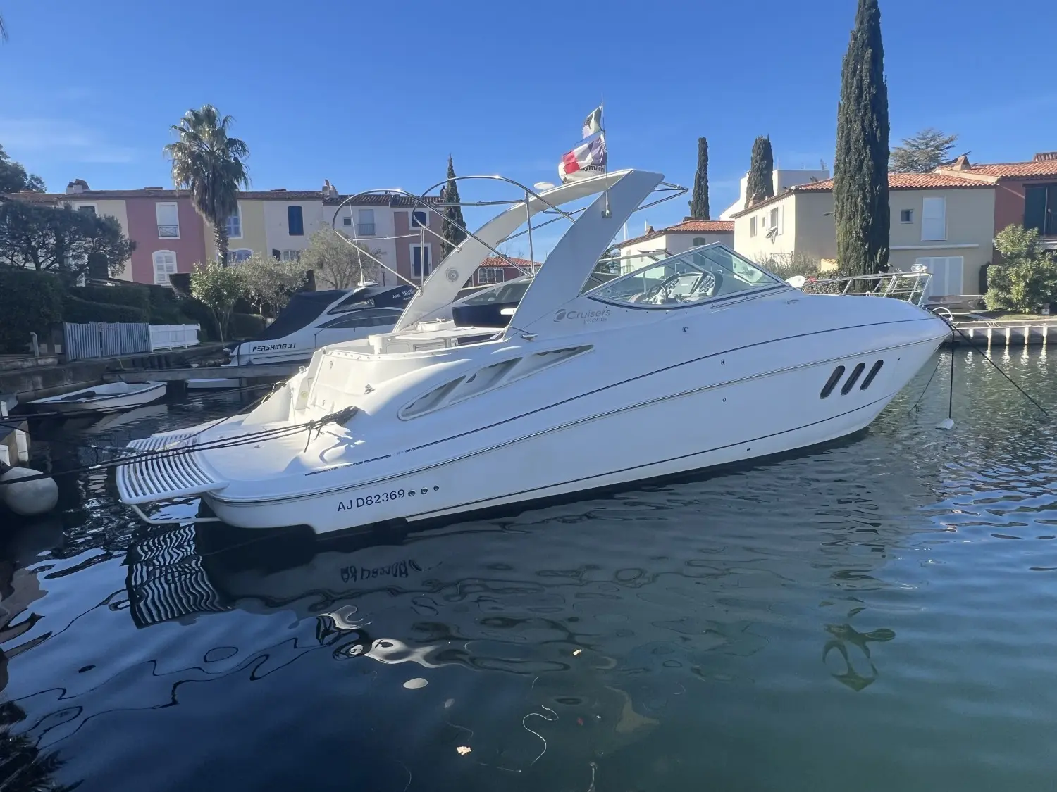 Cruisers Yachts 330 Express — Bateau à moteur blanc vu de trois quarts dans un port résidentiel.