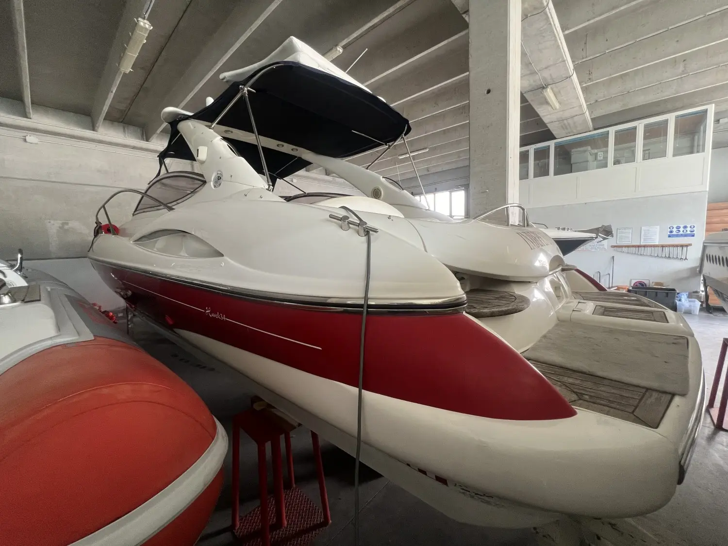 Sunseeker Superhawk 34 — Bateau à moteur blanc et rouge présenté à l’intérieur d’un hangar.