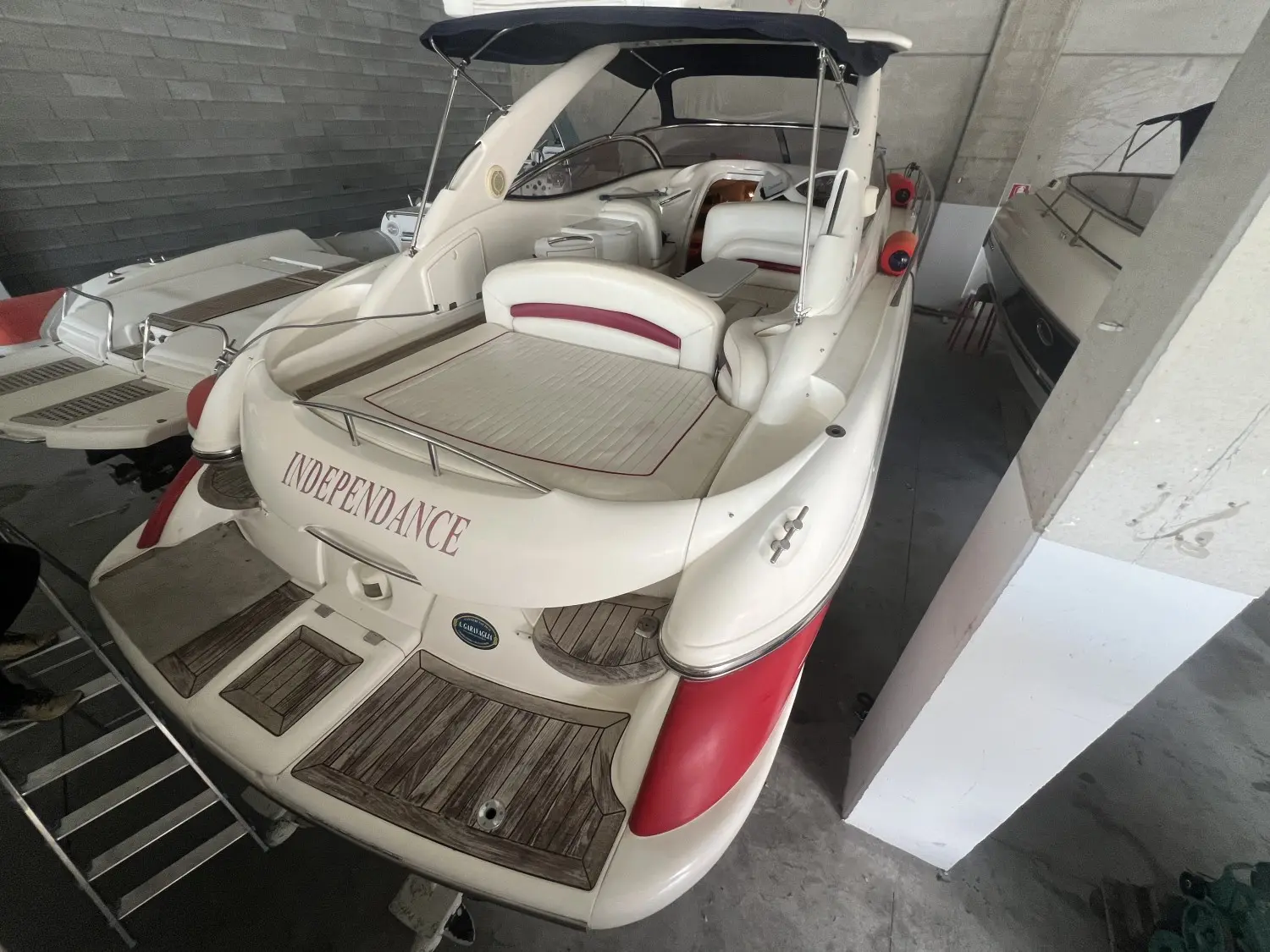 Sunseeker Superhawk 34 — Vue arrière d’un bateau blanc et rouge avec cockpit, bain de soleil et taud.