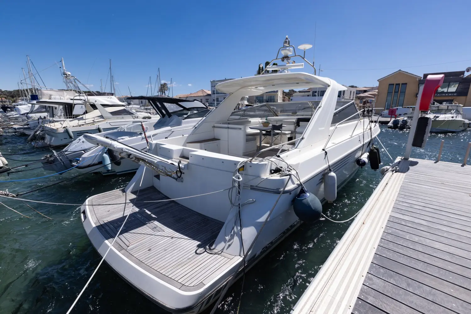 Fairline Targa 42 — Bateau à moteur blanc amarré dans un port, vu de trois quarts arrière.