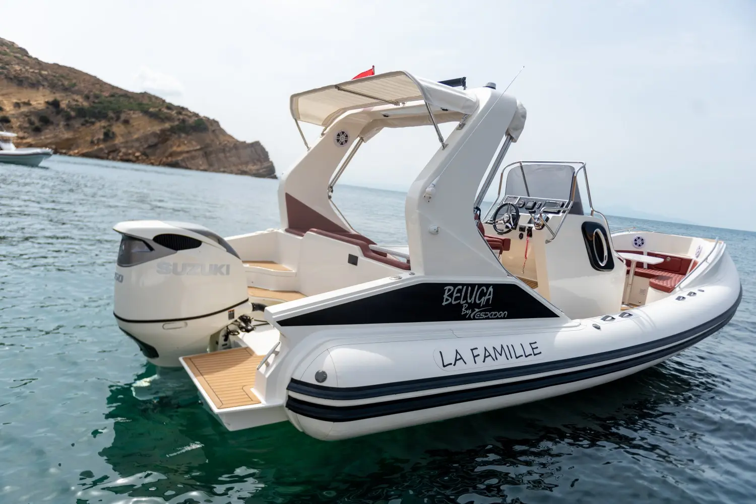 Espadon 800 Beluga — Bateau semi-rigide blanc vu de trois quarts arrière dans une baie.